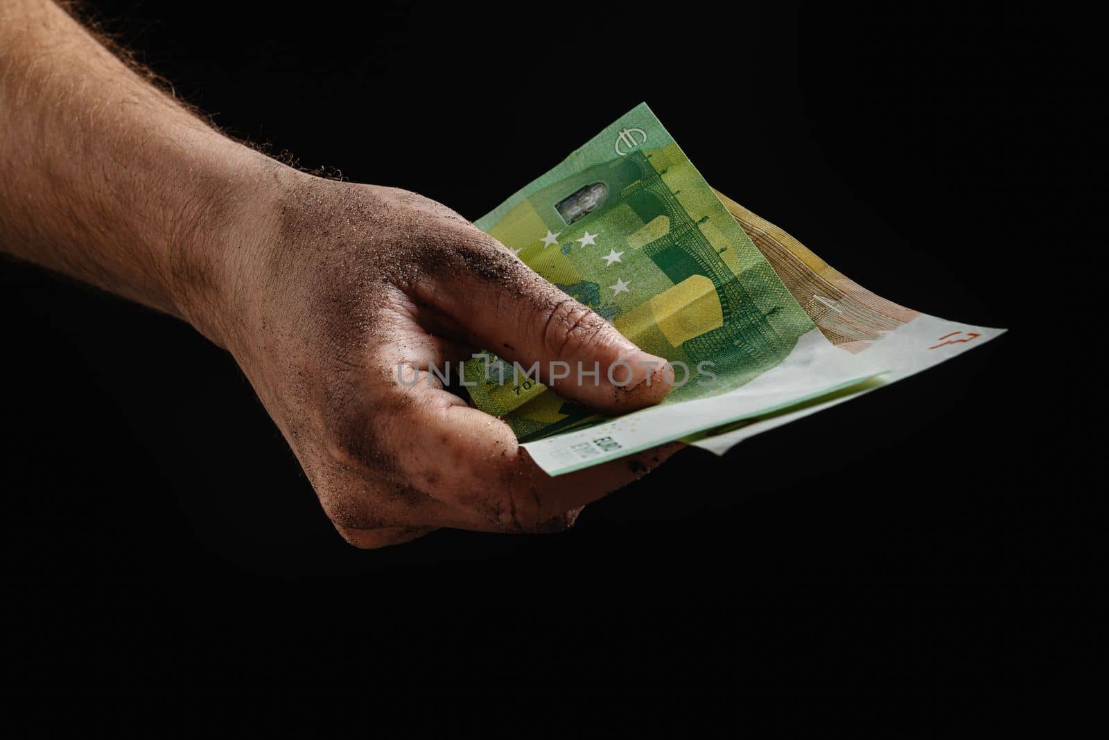 A financial crisis in Europe. Dirty hands of the worker holding money in the black. The concept of bankruptcy and crisis
