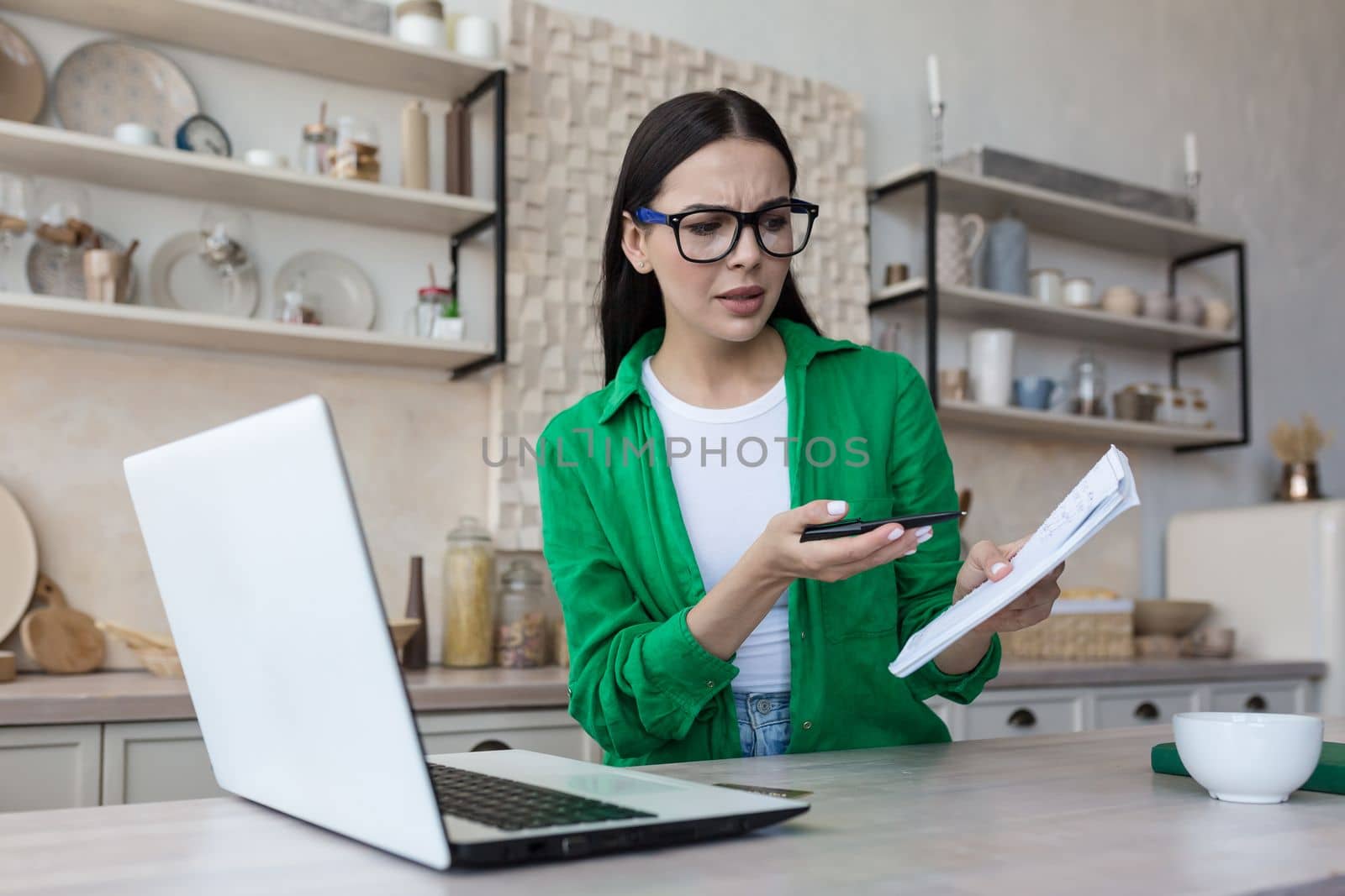 Online business meeting. Young upset woman talking on video call from laptop with tax, bank, creditor. Quarrels, shows a notebook with bills.