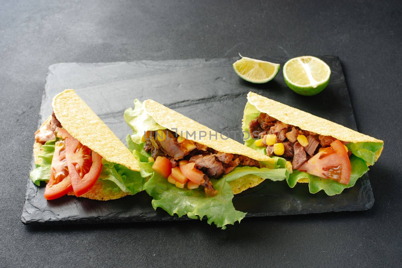 Mexican tacos, vegetables and salsa. Tacos al pastor on a wooden board on a black background. Top view with copy space.