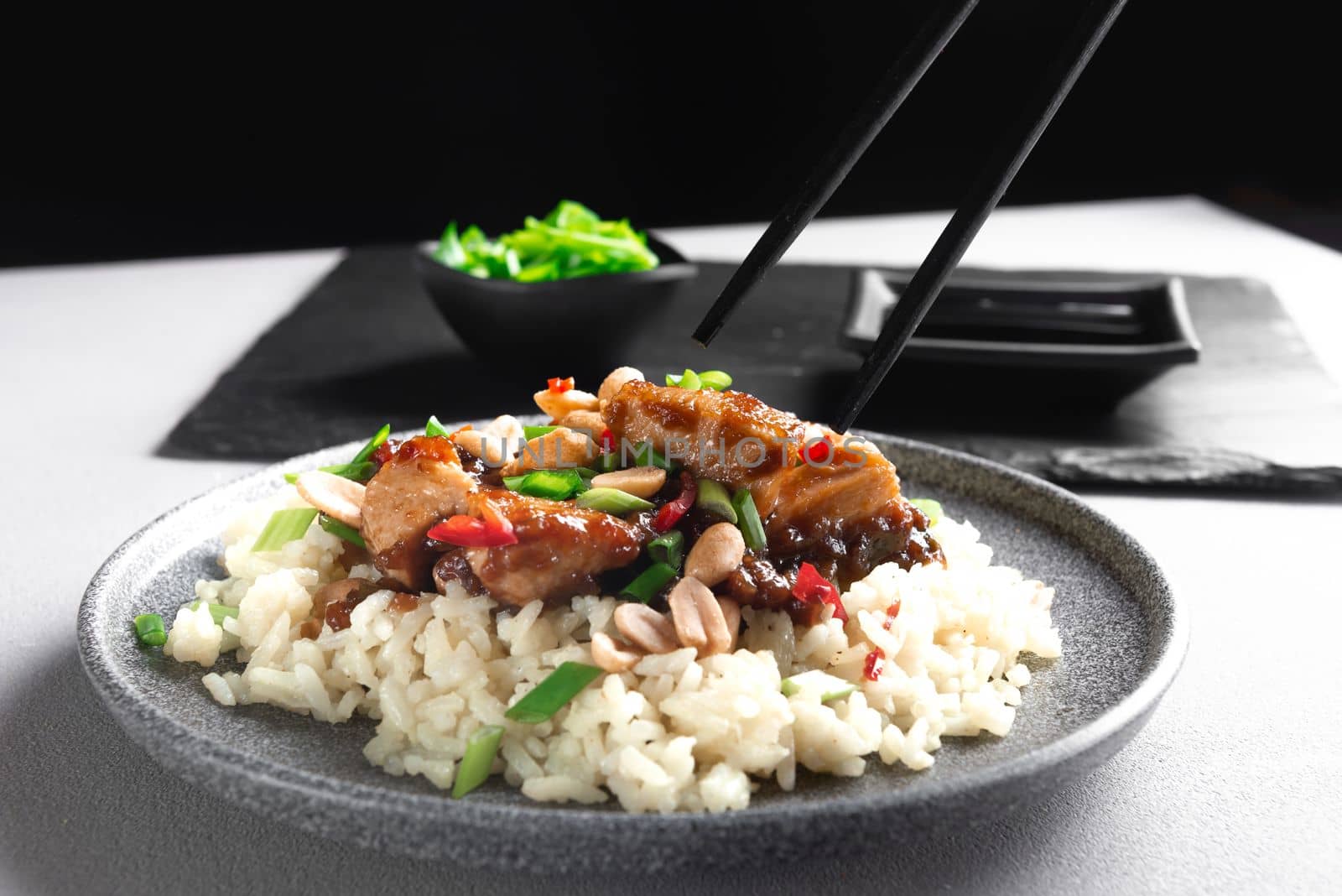 Asian food. Asian food eaten with chopsticks. Kung Pao Chicken and Rice. Kung Pao Chicken or Gong Bao Ji Ding at dark slate background. Sichuan Kung Pao. Top view by gulyaevstudio