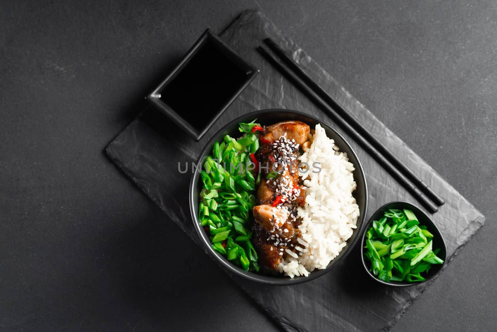 Asian food. Thai food. Rice with chicken and green onions on a dark background. Chinese food. Rice with spicy kung pao chicken on a plate. horizontal view from above.
