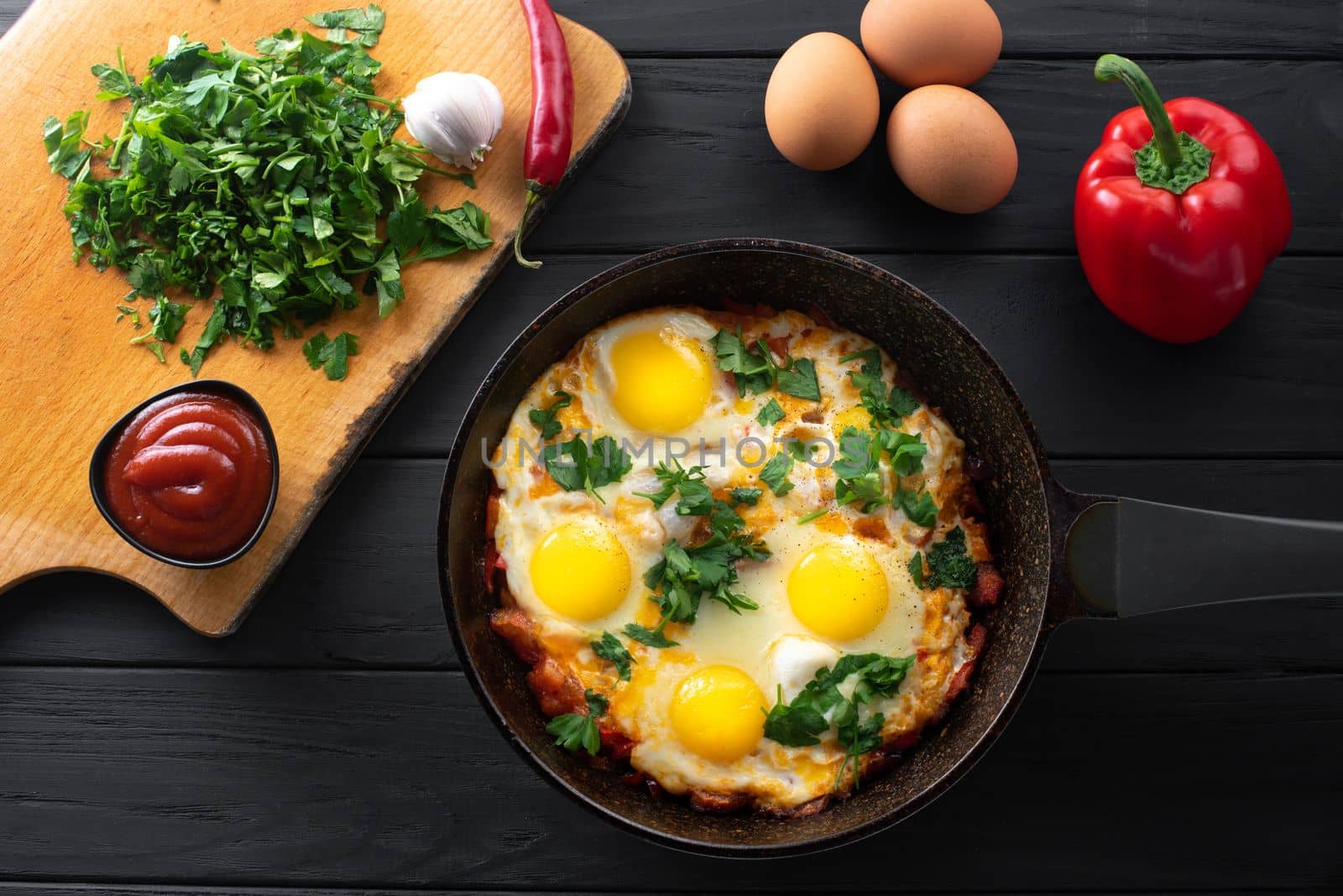 Ingredients for making shakshuka. Shakshuka in an iron skillet with ingredients. Middle Eastern traditional dish. Fried eggs with tomatoes, bell peppers, vegetables and herbs, scrambled eggs.