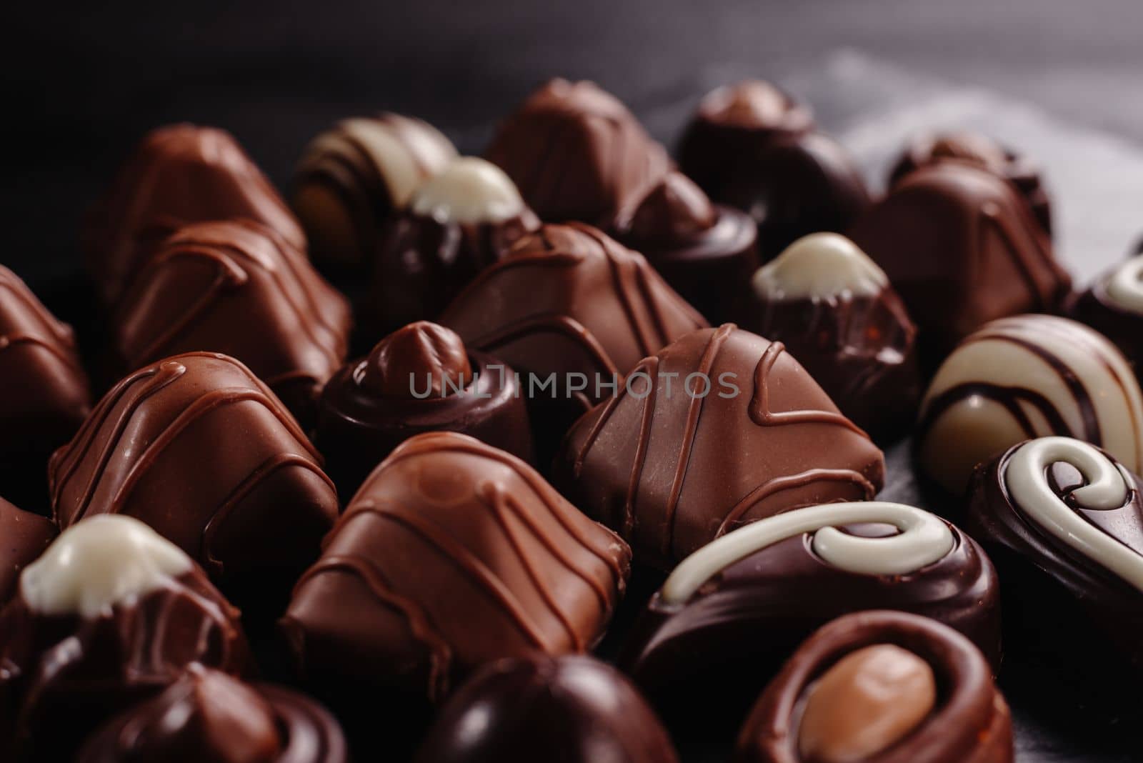 chocolate candies with different tasty, sweet food background. Chocolate candy on a dark background. Top view. Lots of different chocolates. An assortment of delicious chocolates