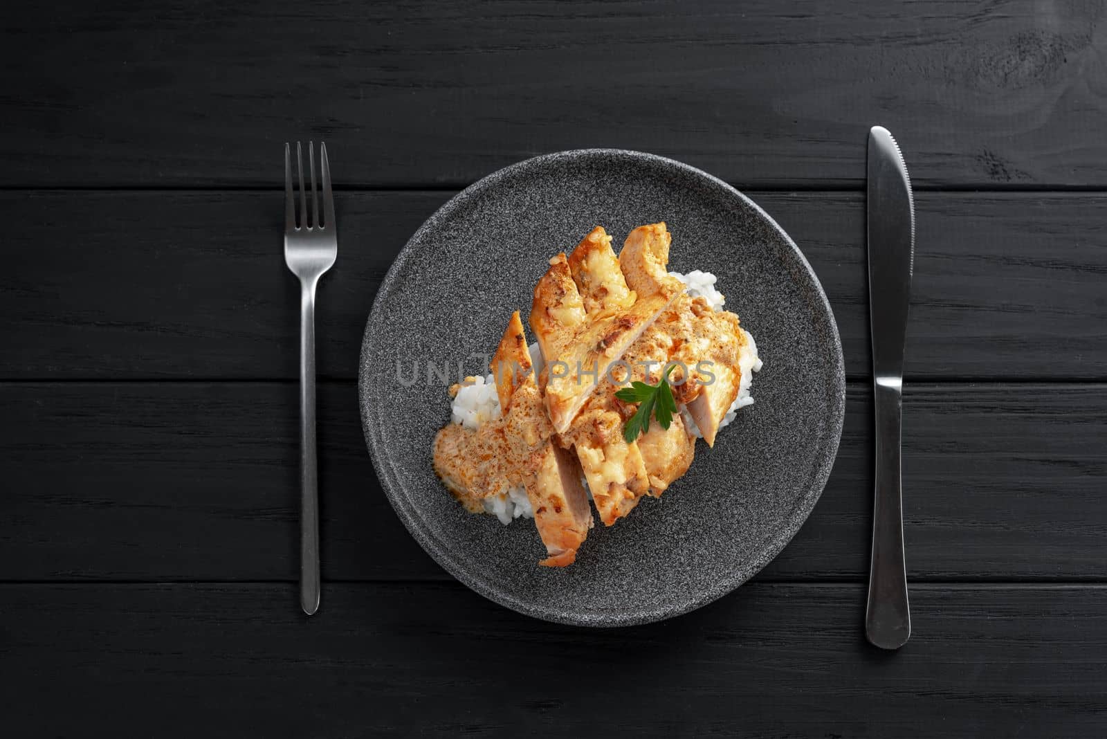 Chicken breast in cream sauce with rice top view. Plate with chicken breast on dark wooden background. Top view by gulyaevstudio