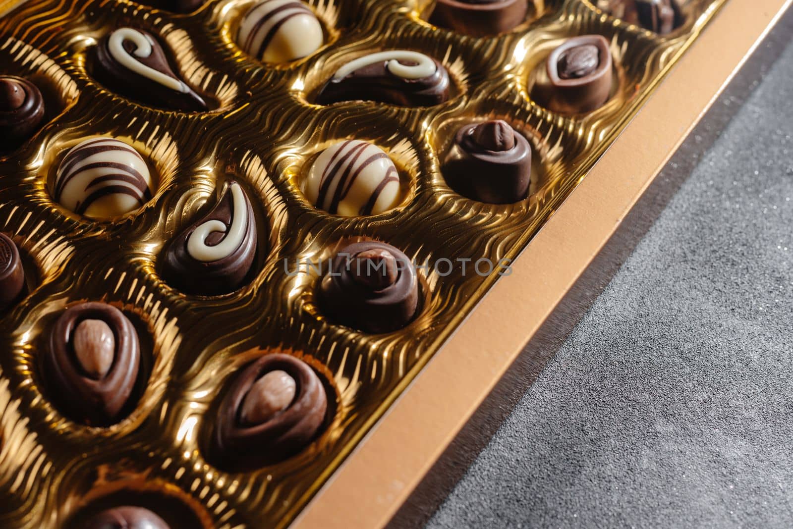 A box of different chocolates. Chocolate assortment mix on the black table, top view.