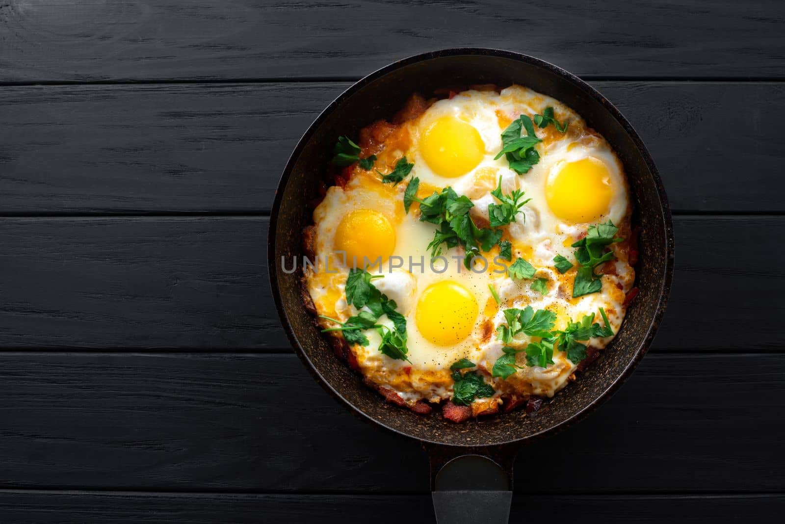 Homemade rustic fried eggs with tomatoes and parsley greens in a pan by gulyaevstudio
