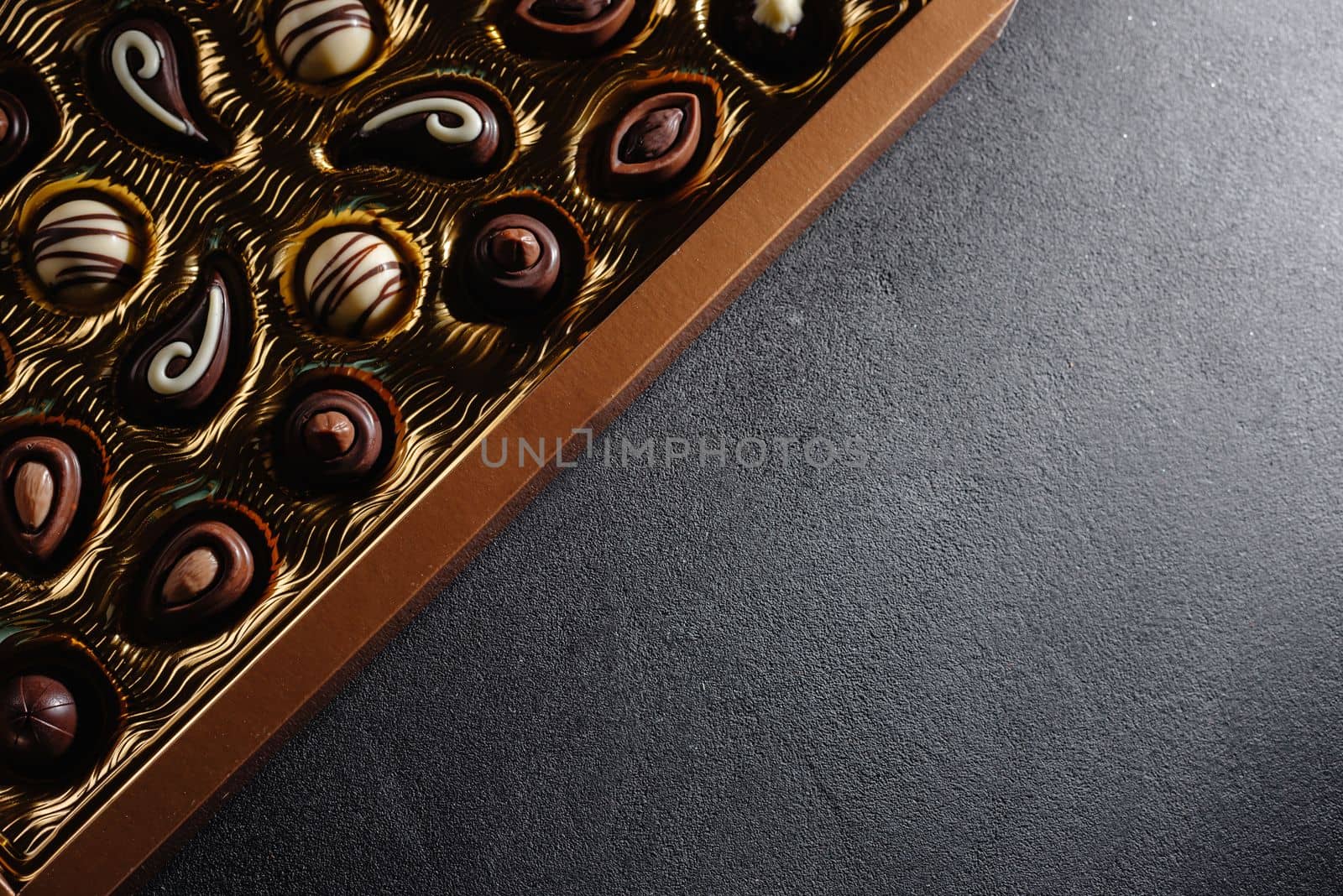 A box of different chocolates. Chocolate assortment mix on the black table, top view. Copy space. by gulyaevstudio