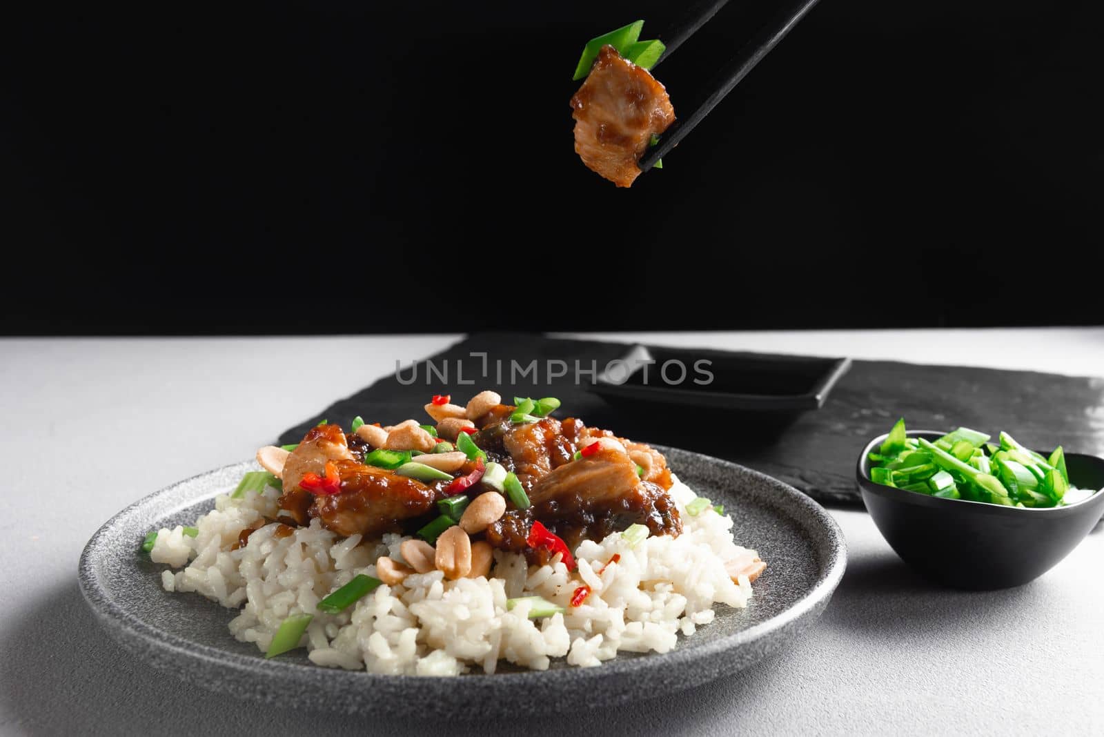 Asian food. Asian food eaten with chopsticks. Kung Pao Chicken and Rice. Kung Pao Chicken or Gong Bao Ji Ding at dark slate background. Sichuan Kung Pao. Top view.