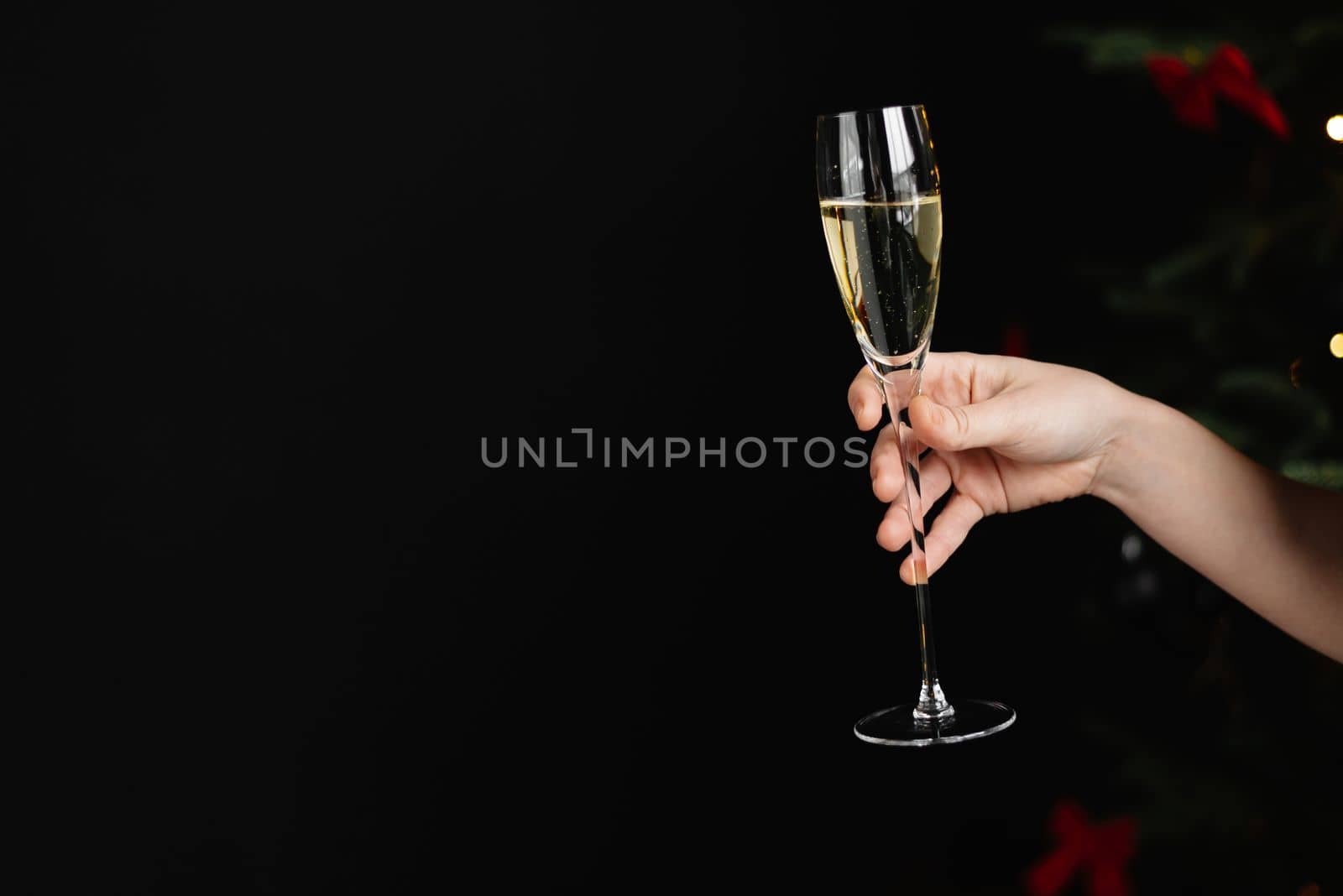 A woman's hand with a glass of champagne on a dark background