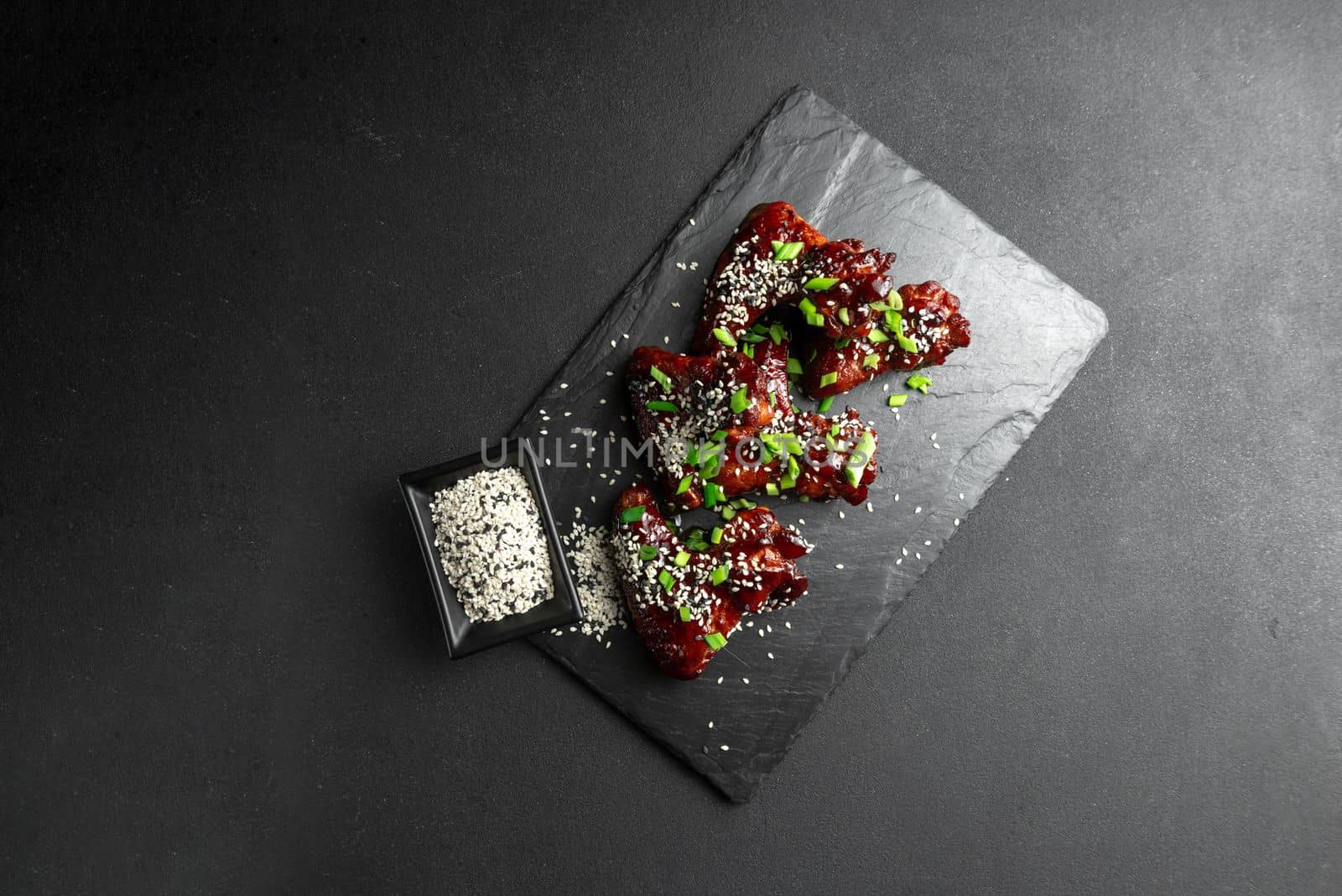 Asian Food. Homemade Korean-style spicy chicken wings with sesame seeds. Chicken wings. Traditional asian recipe. Dark background. Top view