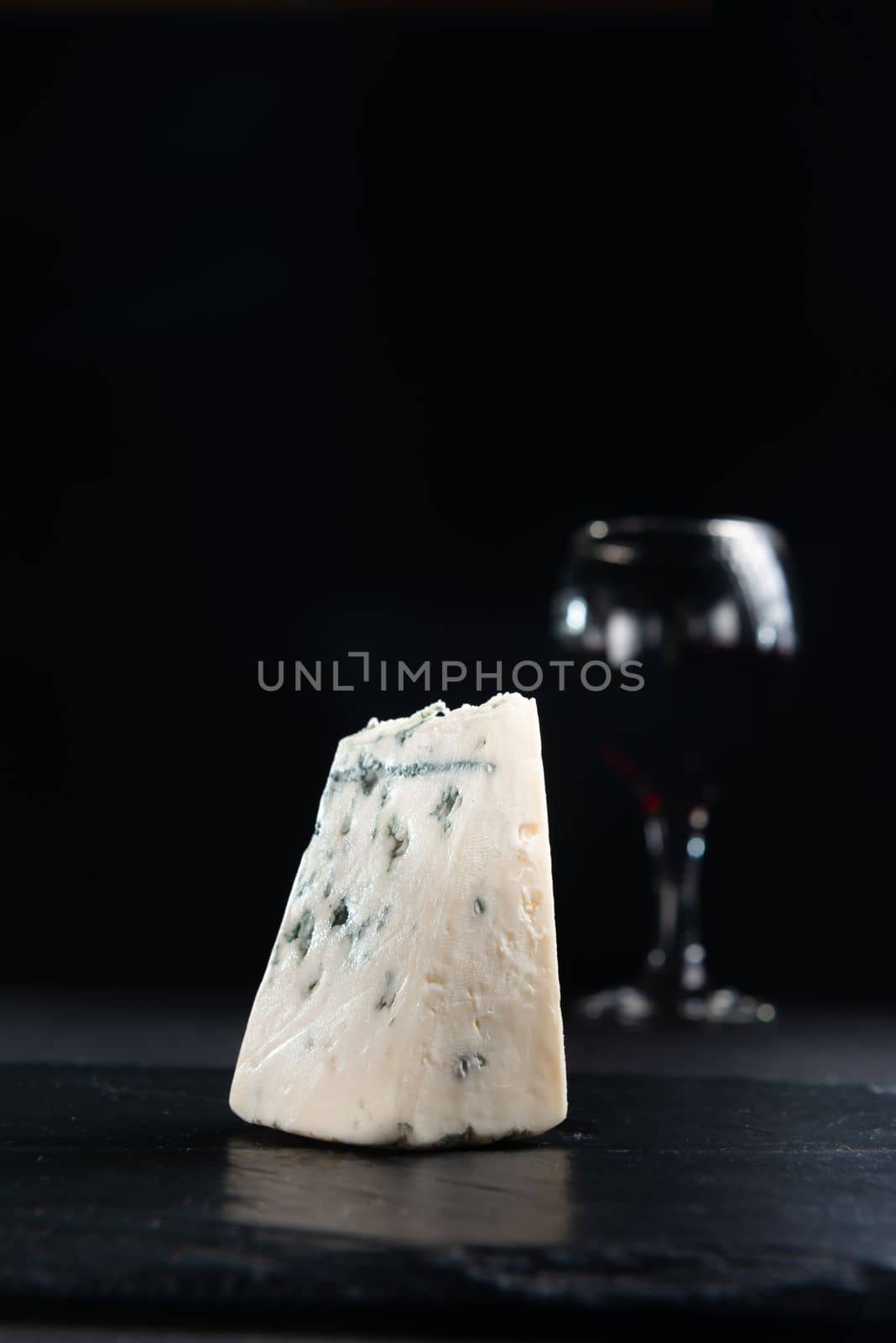 Slice of blue mold cheese Roquefort cheese on a dark background. Close-up view with copy space