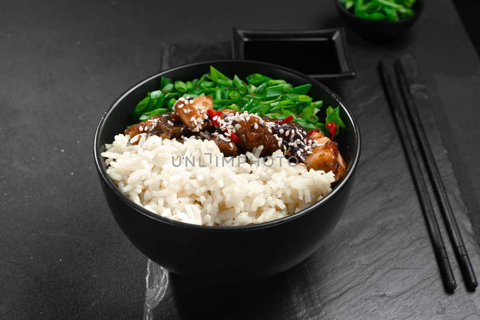 Asian food. Asian-style kung pao chicken with rice and green onions. Kung Pao chicken. Gong Bao Ji Ding on a dark concrete background. Sichuan kung pao is a Chinese dish with chicken meat by gulyaevstudio