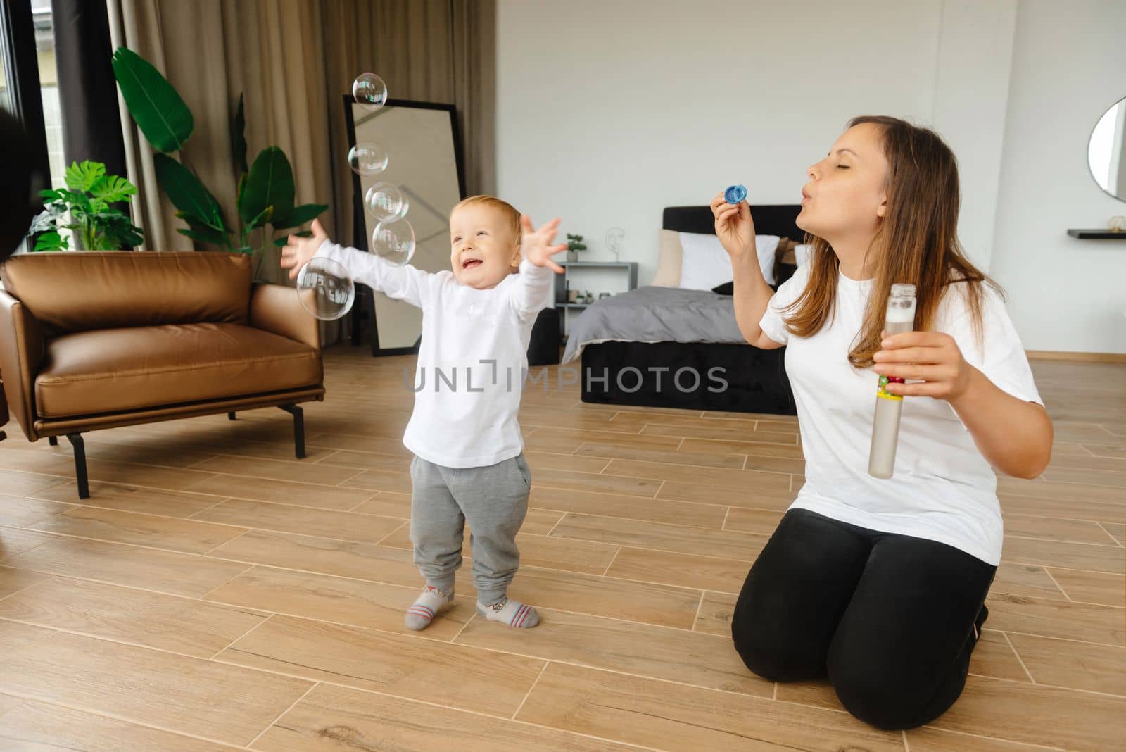 mother and son playing with soap bubbles. The child enjoys the soap bubbles. Family sitting at home playing with soap bubbles by gulyaevstudio