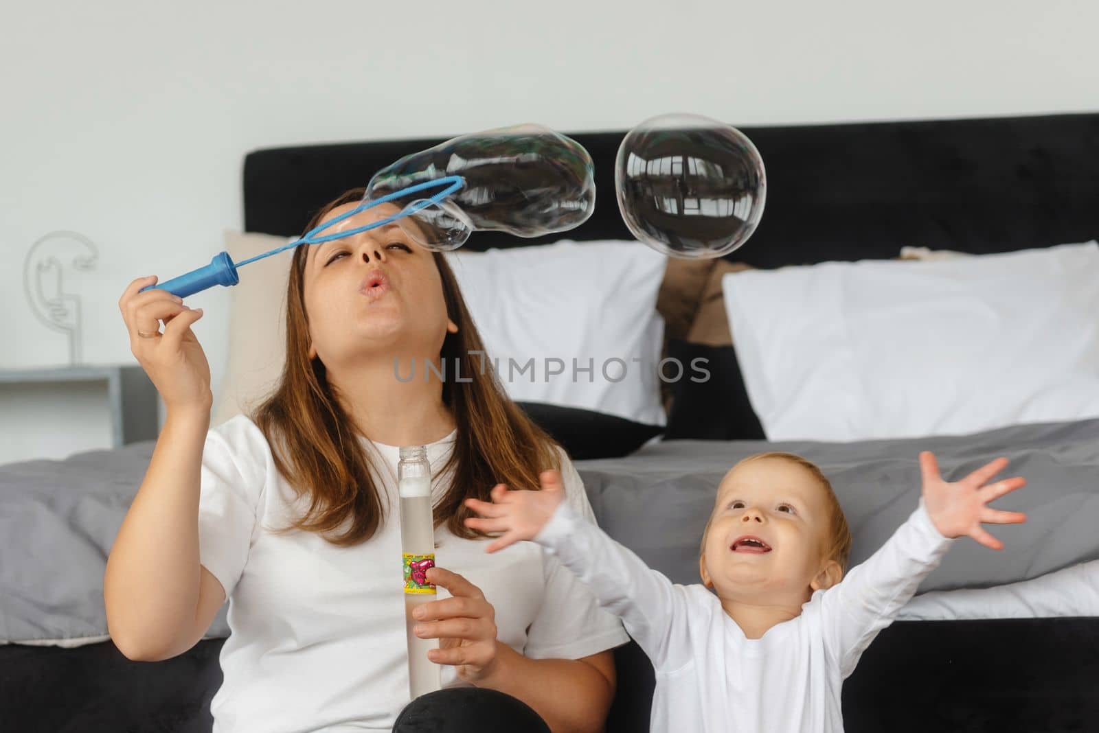 mother and son playing with soap bubbles. The child enjoys the soap bubbles. Family sitting at home playing with soap bubbles. A happy childhood and a healthy family, happy family relationships