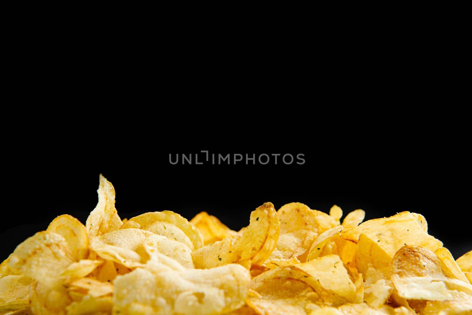Lots of fried chips on a black background. Isolate. A place to write text. Copy space for text.
