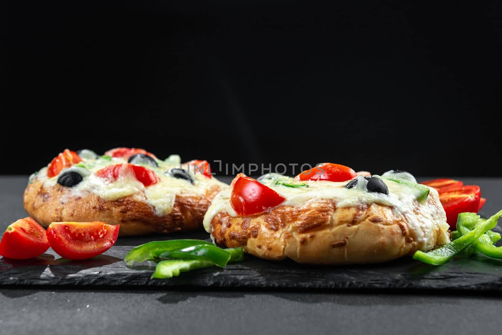 Homemade pizza with vegetables for breakfast on black background with blank space for text.