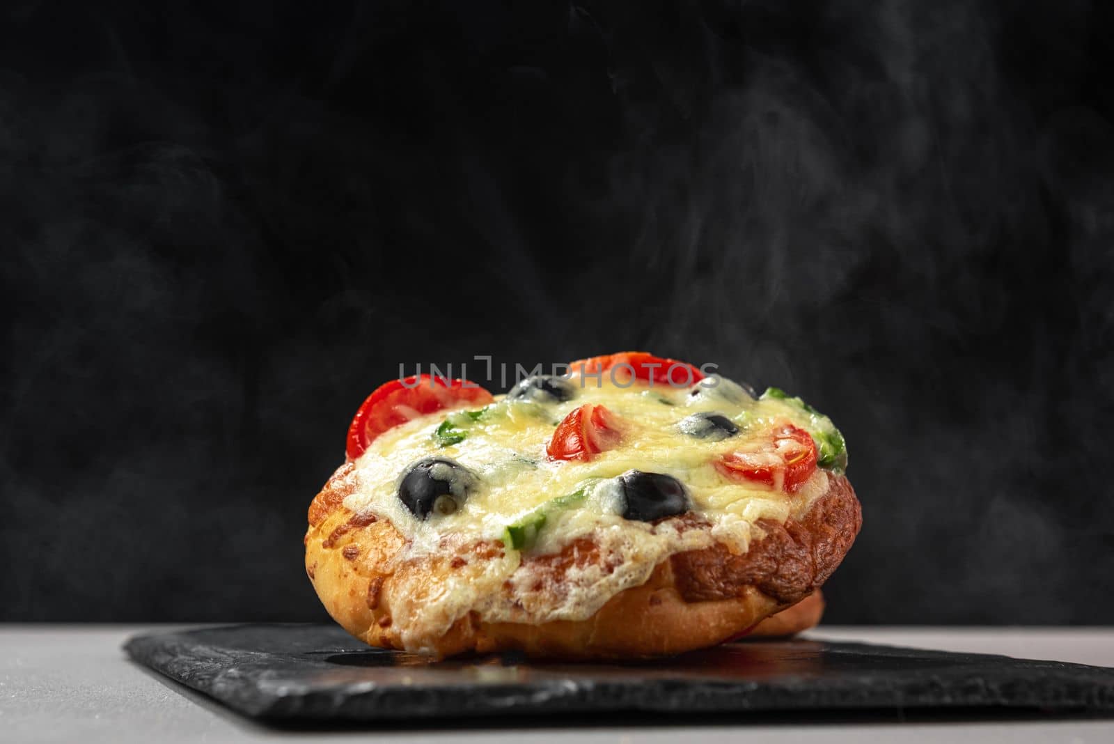 Homemade pizza hot goes steaming on black background. by gulyaevstudio