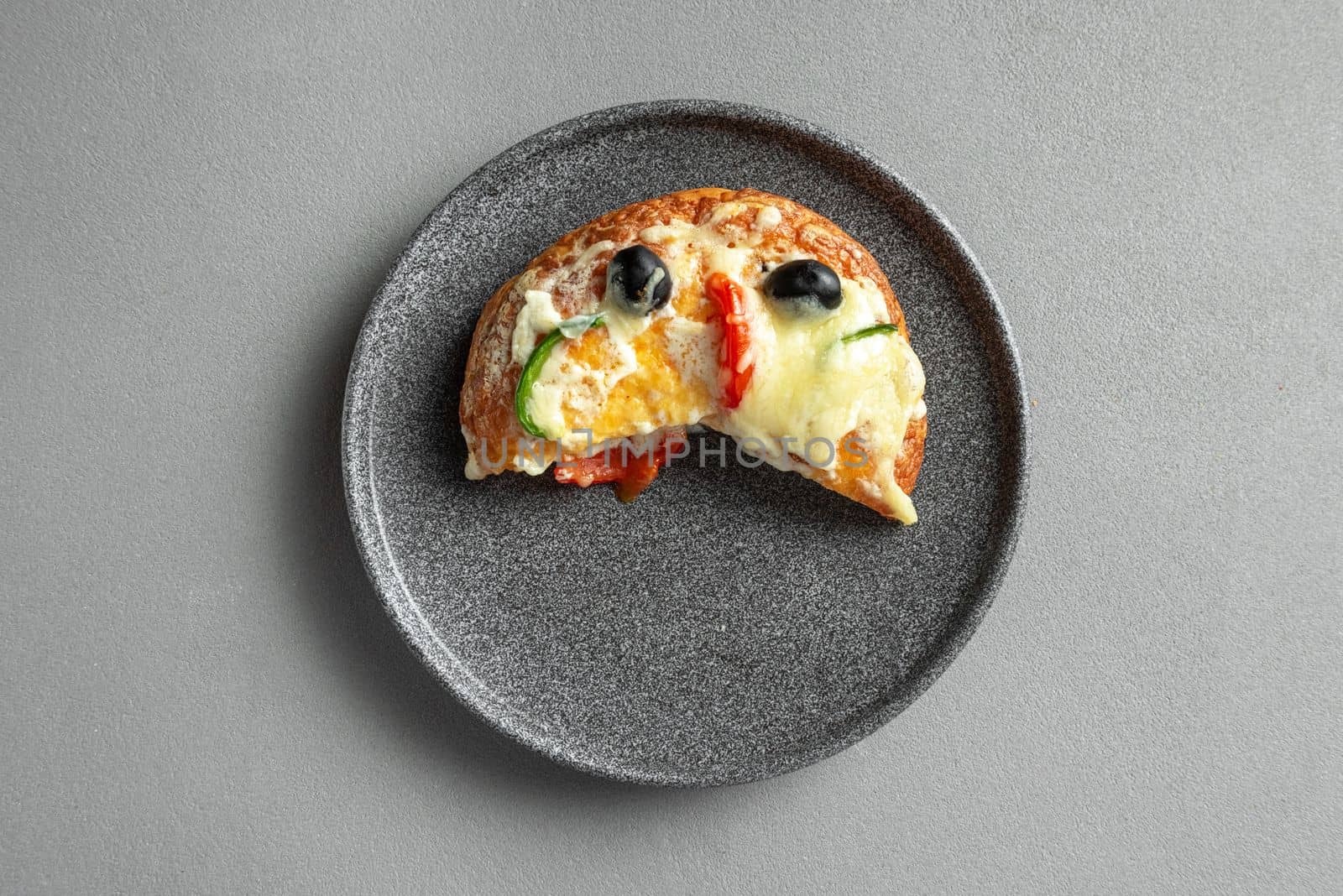 Slice of Indian pizza on a plate on a gray background.