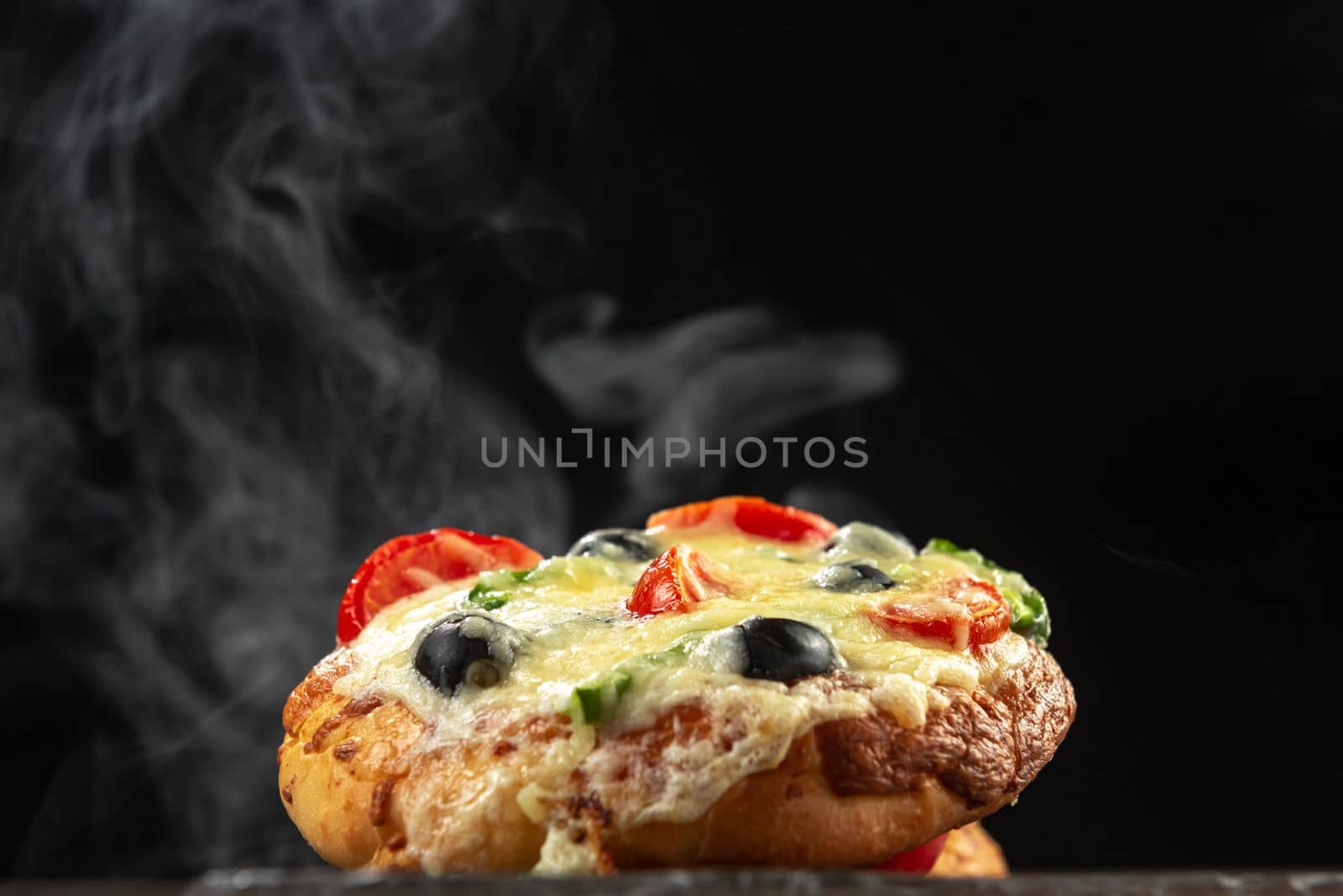 Indian hot pizza goes steaming. Homemade Indian pizza on small tortillas on a black background. Indian pizza on tortillas. Modern Indian culture in food. by gulyaevstudio