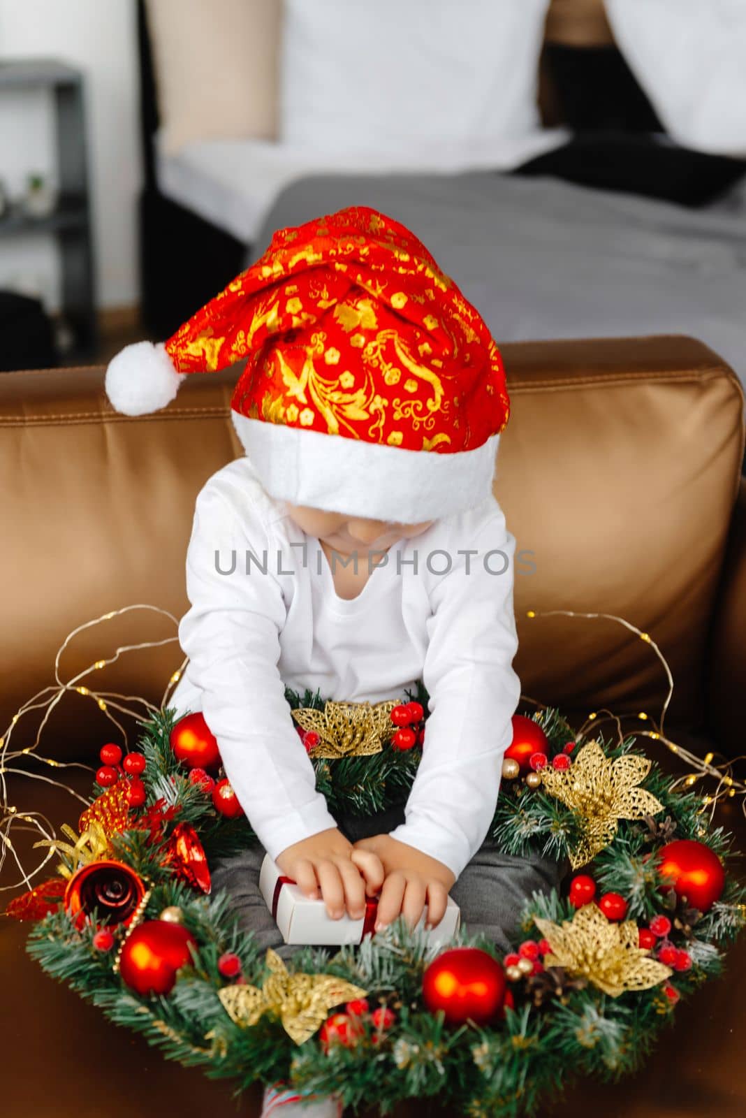 A boy opens a Christmas present for Christmas. A child sits on an armchair and holds a gift by gulyaevstudio