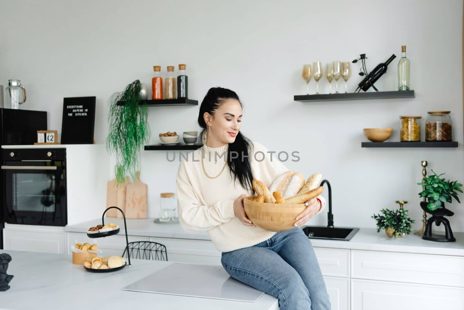 A woman sits in her kitchen holding a bread basket. Enjoying the little things. Lykke Concepts. Relaxation Concepts.