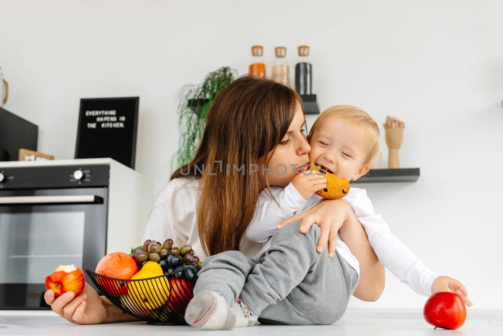 Happy Family Mom hugging baby and eating apples and healthy food. Reducetarian Eating Enjoying Vegetable Food by gulyaevstudio
