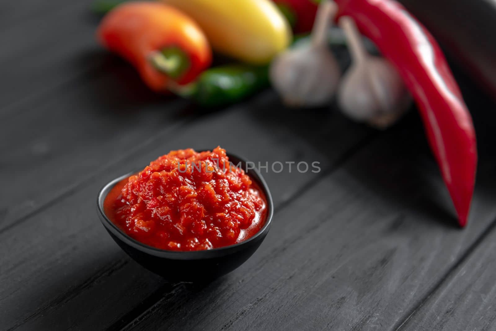 Hot chili pepper paste. Red sauce on a wooden background. Ajika or ajika in Georgian cuisine or harissa in Arab cuisine. View from above