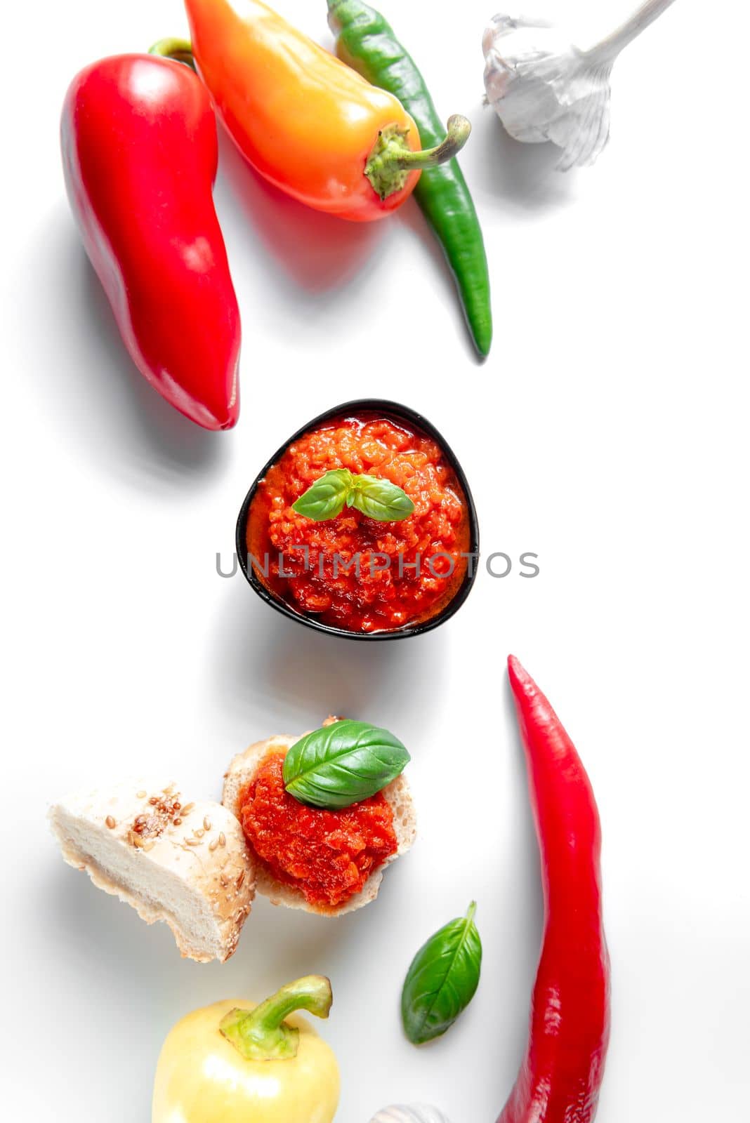 A bowl of chili sauce on a white background. Spicy Ajika with chili peppers on white background. by gulyaevstudio