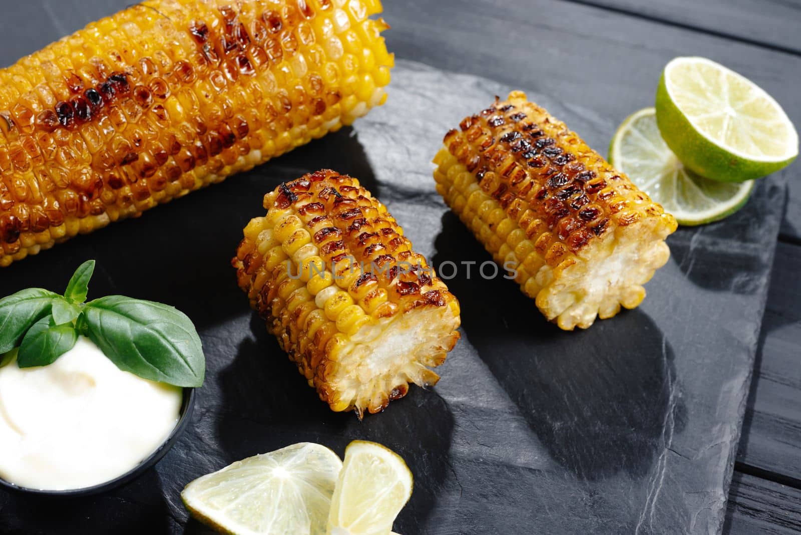 Grilled corn on the cob with butter and salt on the grill plate, close-up, top view