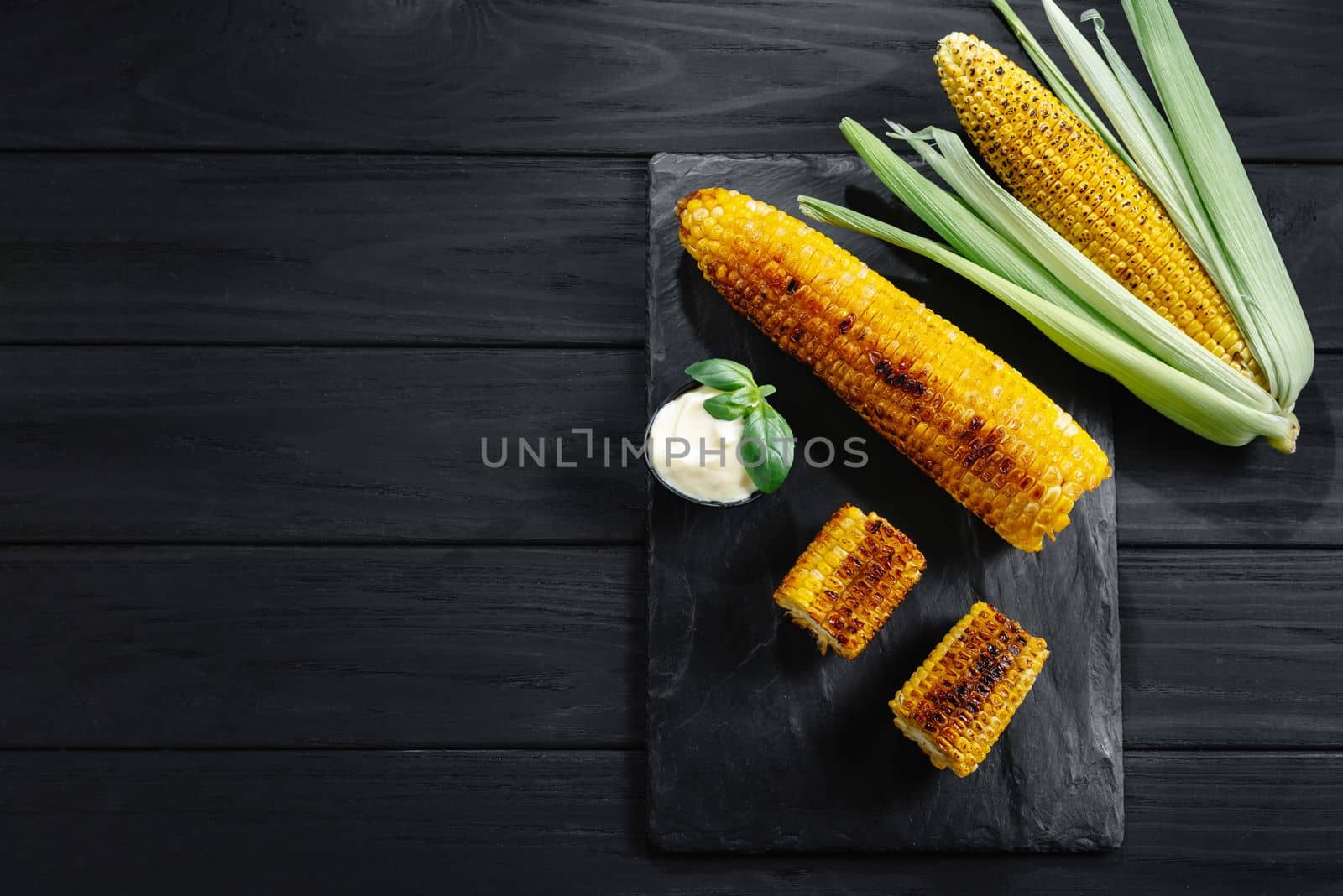 Grilled corn on slate to serve with sauce and lime. Top view and copy space