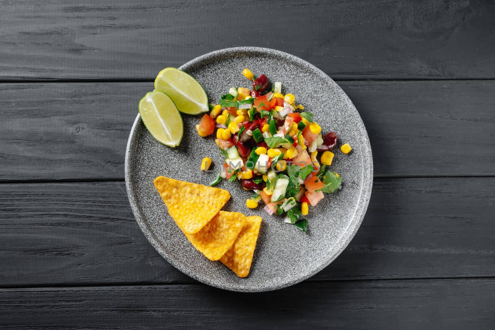 Texas caviar on a black wooden background. Top view. Texas dish with chips and nachos on a gray plate. Reducetarian, flexitarian, pescatarian eating