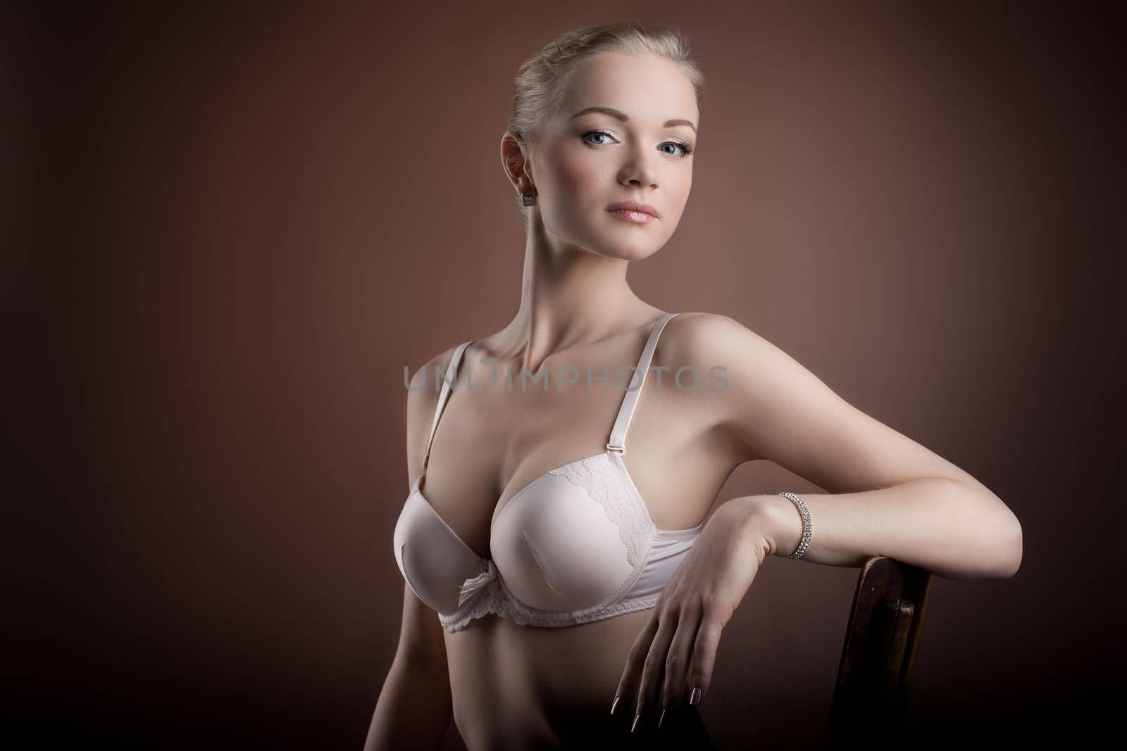 Beautiful woman portrait in white bra on brown background