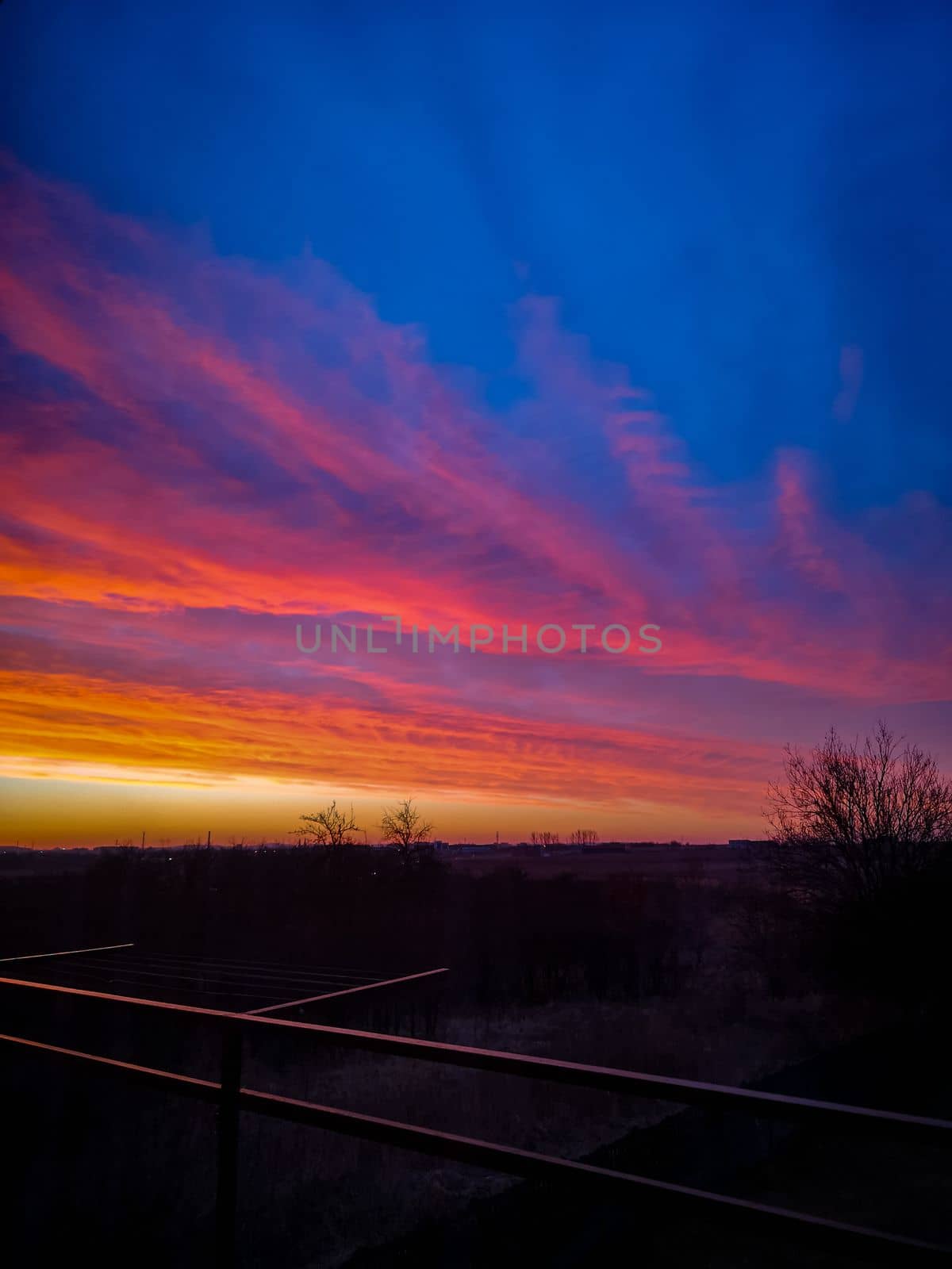 Beautiful colorful morning sunrise full of clouds seen from balcony with long metal railings by Wierzchu