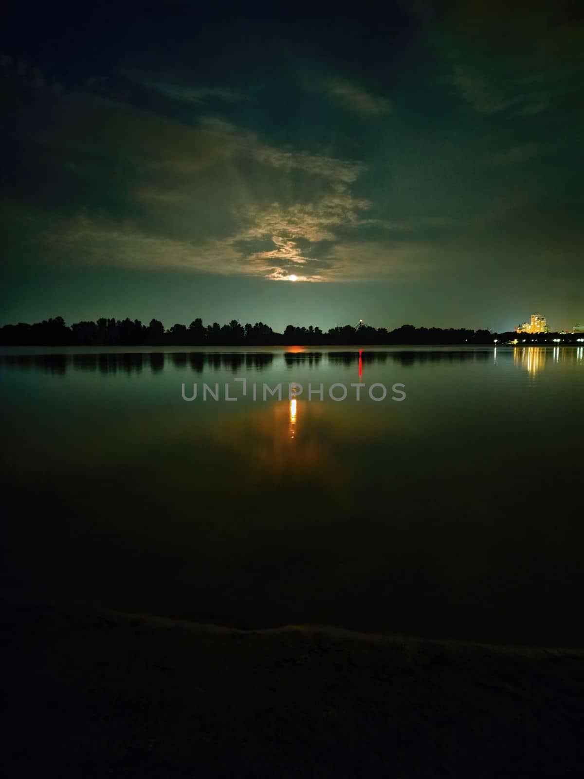 Color photography of evening nature by the river. Rising full moon above the trees. Beautiful reflection of the moon path in the water. by Nickstock