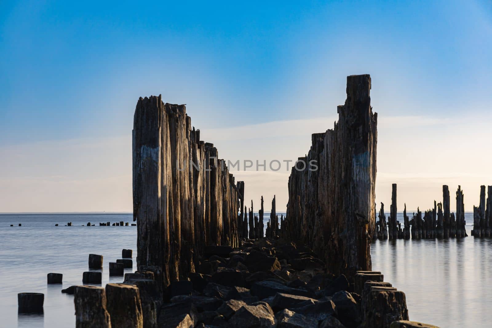 Beautiful landscape of coast of Baltic sea and old wooden breakwater at sunny cloudy morning by Wierzchu