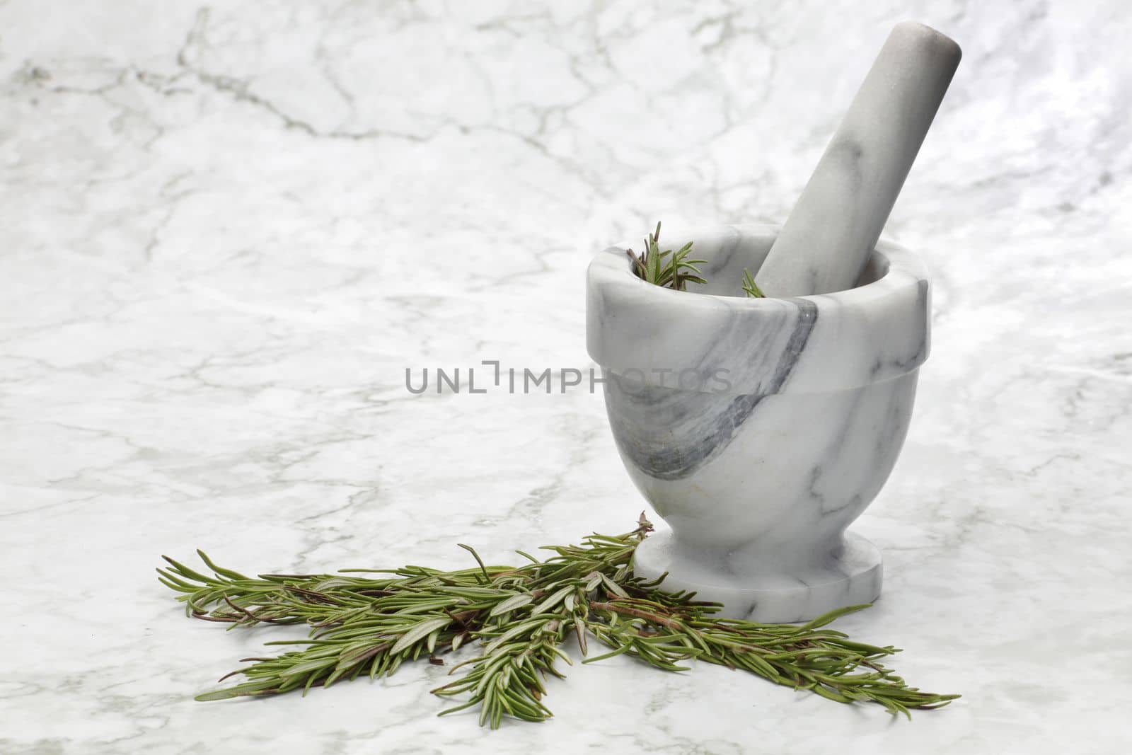 Rosemary herbs and a mortar and pestle on grey and white marble kitchen surface