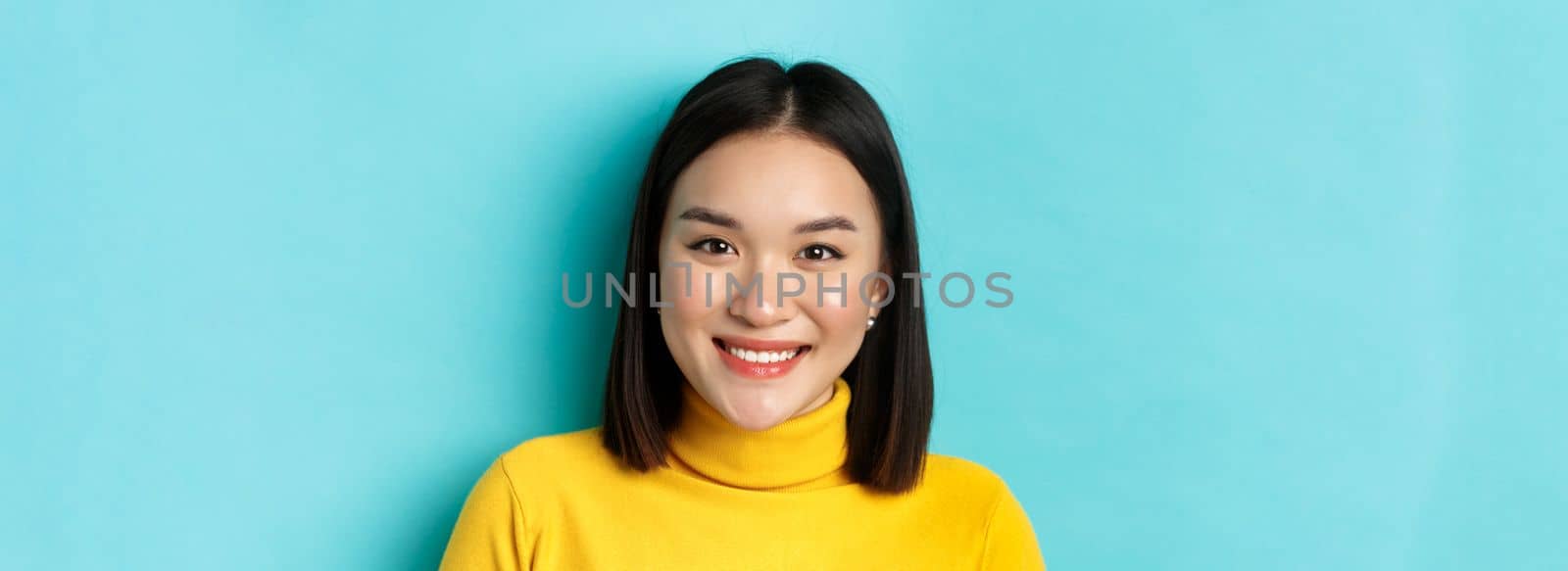 Beauty and skincare concept. Close up of smiling asian female model with perfect skin and white teeth, standing over blue background by Benzoix