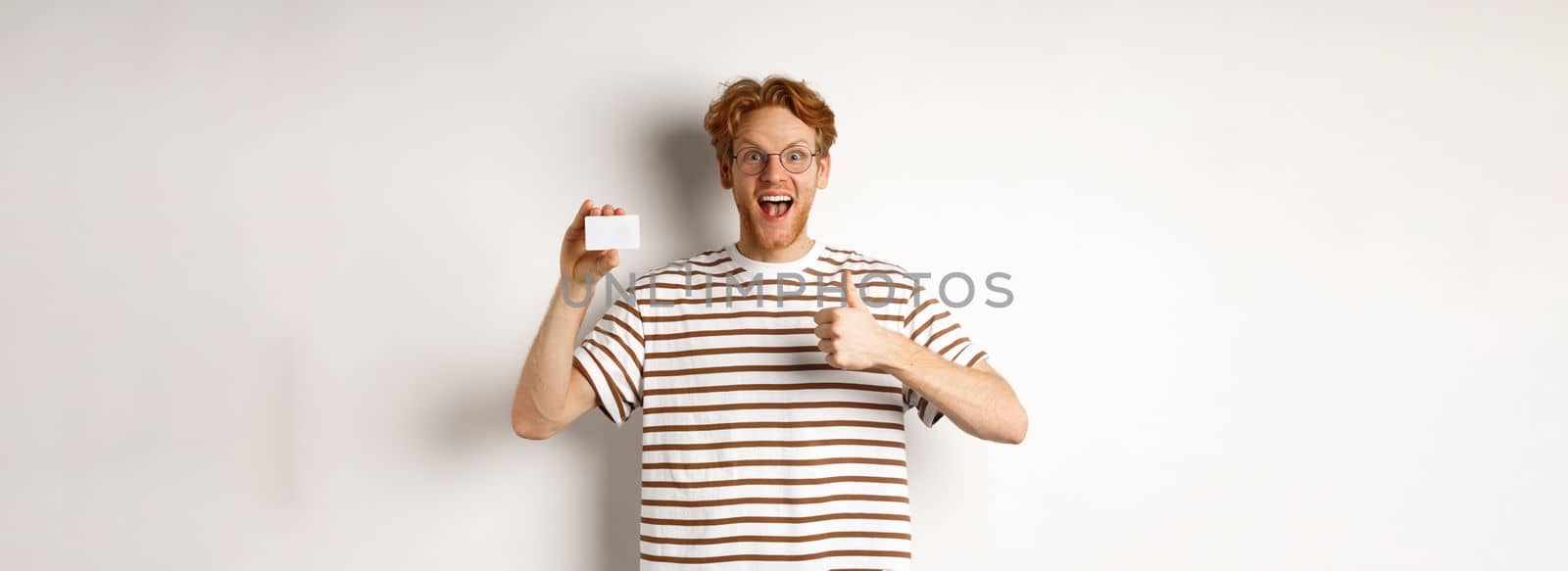 Shopping and finance concept. Satisfied male bank client showing thumbs-up and plastic credit card, smiling happy at camera.