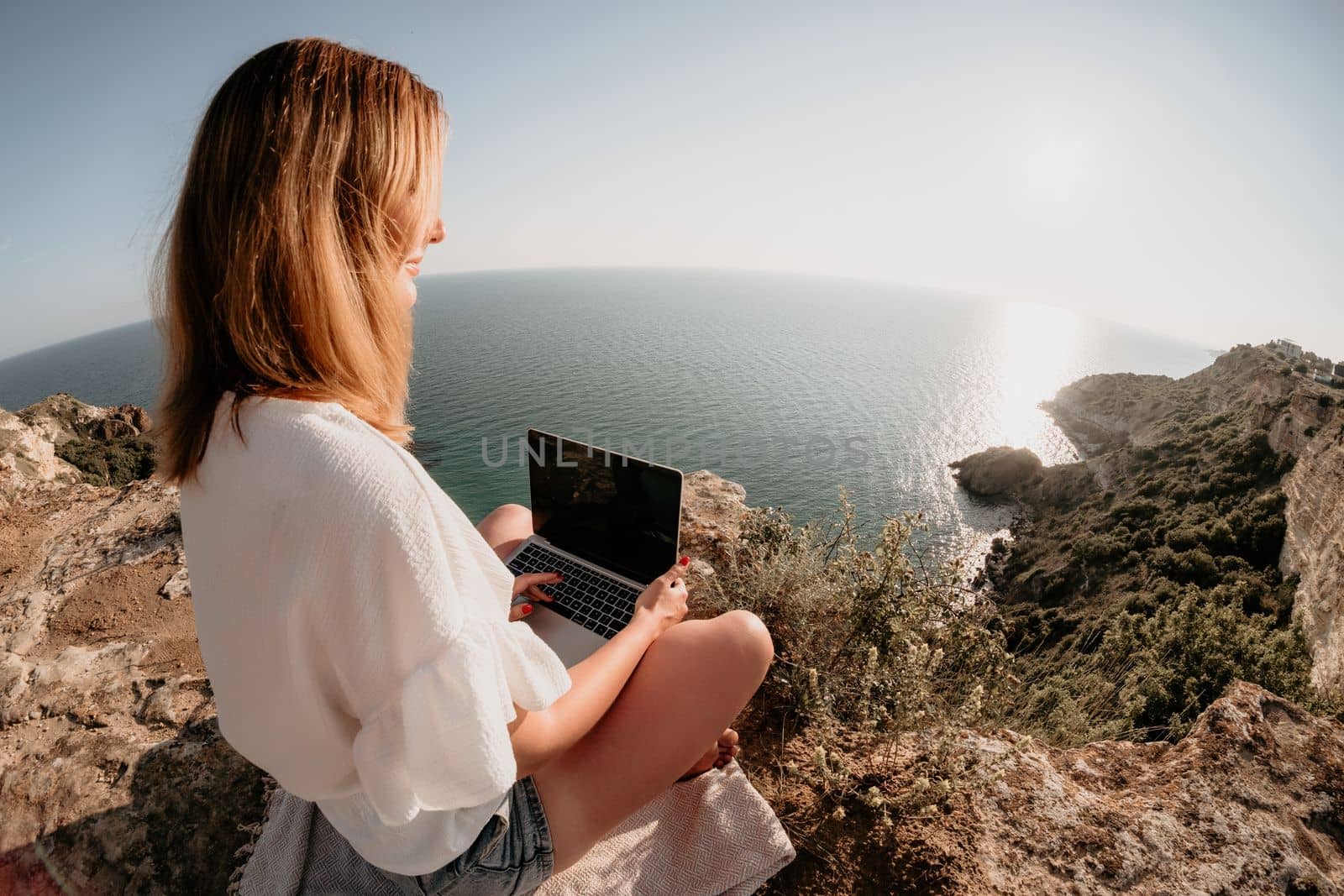 Woman sea laptop. Business woman in yellow hat working on laptop by sea. Close up on hands of pretty lady typing on computer outdoors summer day. Freelance, digital nomad, travel and holidays concept.