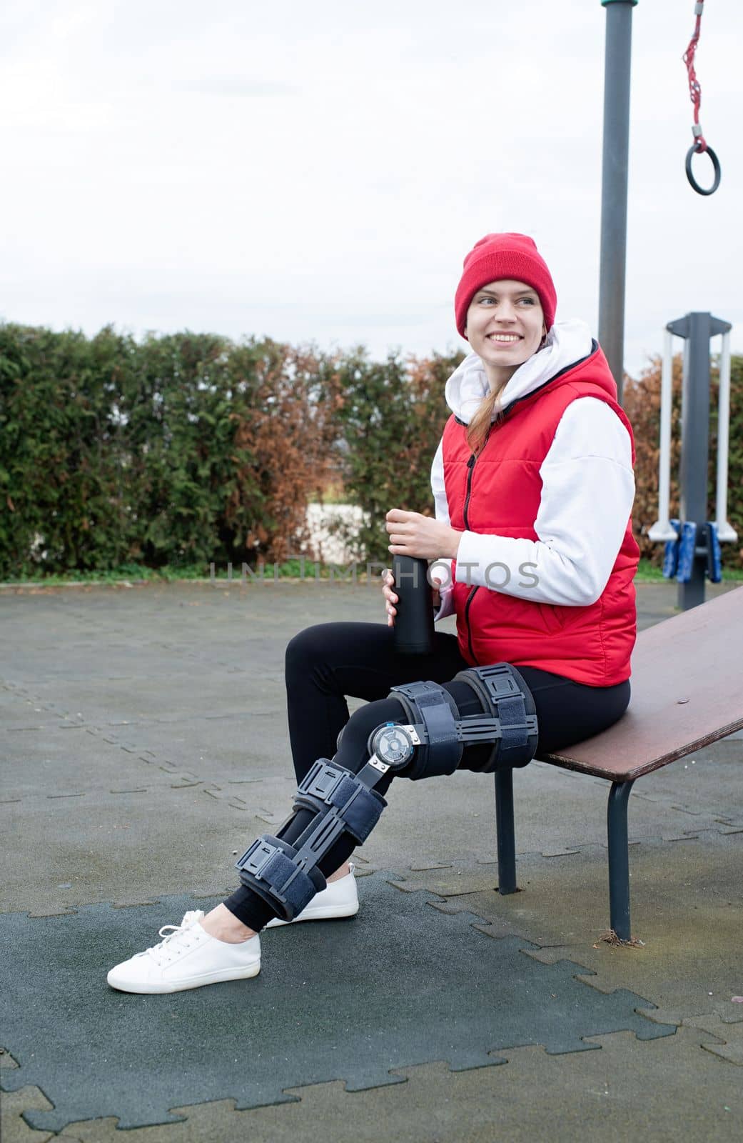 Woman wearing knee brace or orthosis after leg surgery working out in the park by Desperada