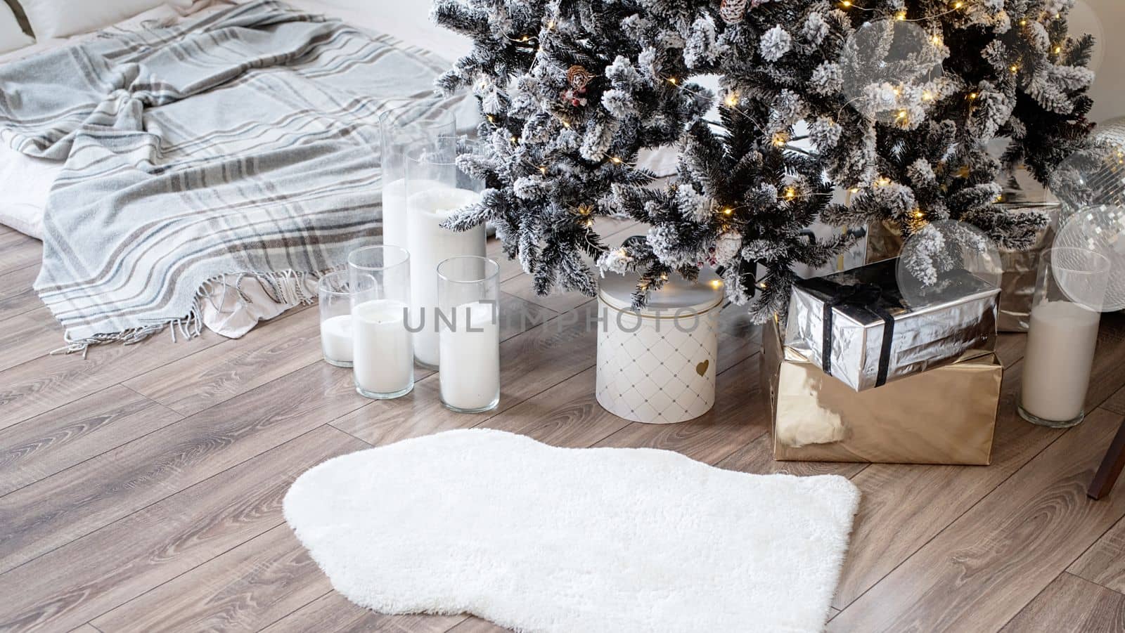 Woman in warm white winter sweater lying in bed at home at christmas eve holding cup with marshmallows, fir tree behind by Desperada