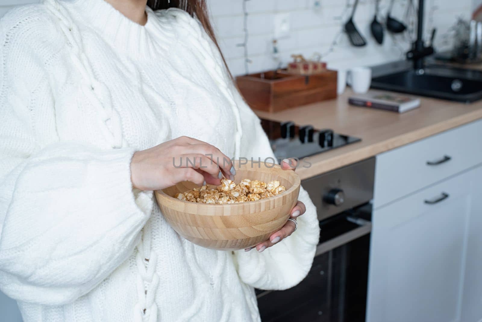 Merry Christmas and Happy New Year. Woman in warm white winter sweater lying in bed at home at christmas eve holding cup with marshmallows, fir tree behind