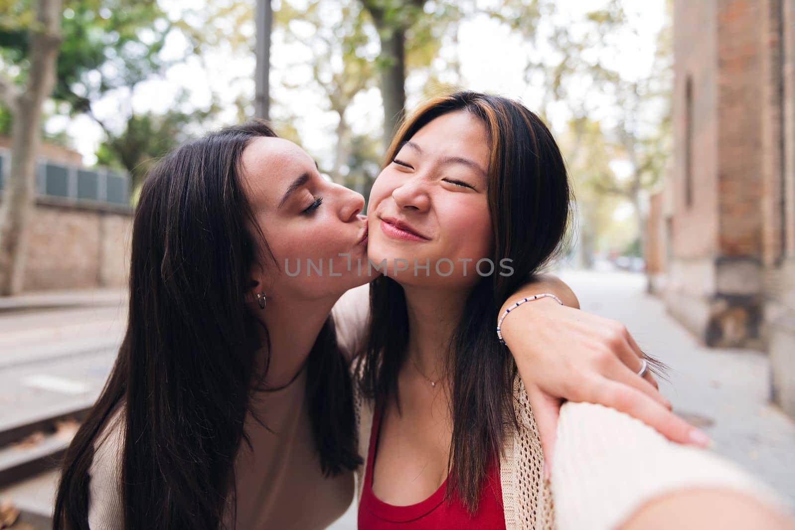 selfie of two young women kissing happy and having fun while they date, concept of friendship and love between people of the same sex