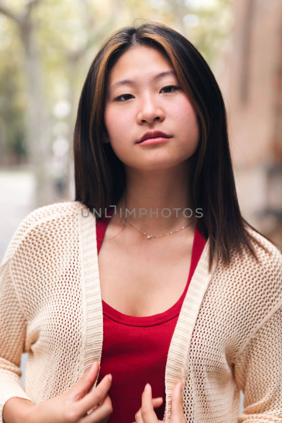 vertical portrait of a serious young asian woman looking at camera, concept of youth and beauty