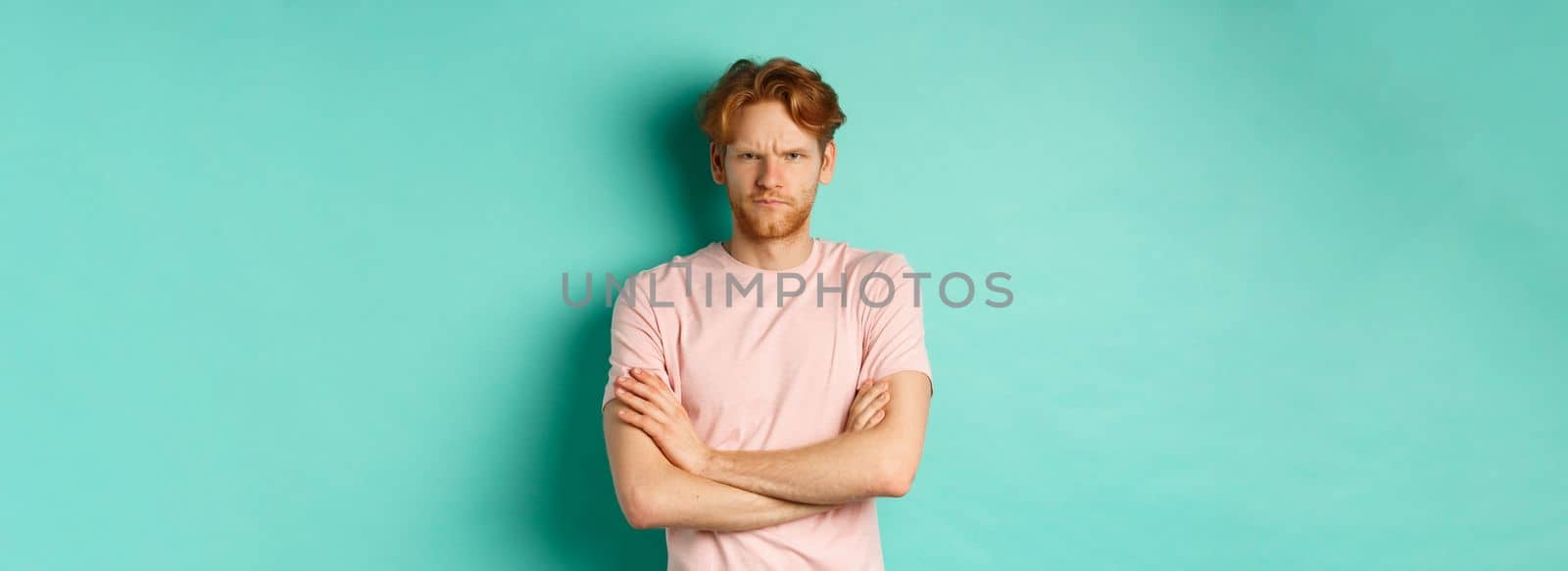 Gloomy redhead guy feeling offended, frowning upser with arms crossed on chest, looking insulted and sulking, standing over mint background by Benzoix