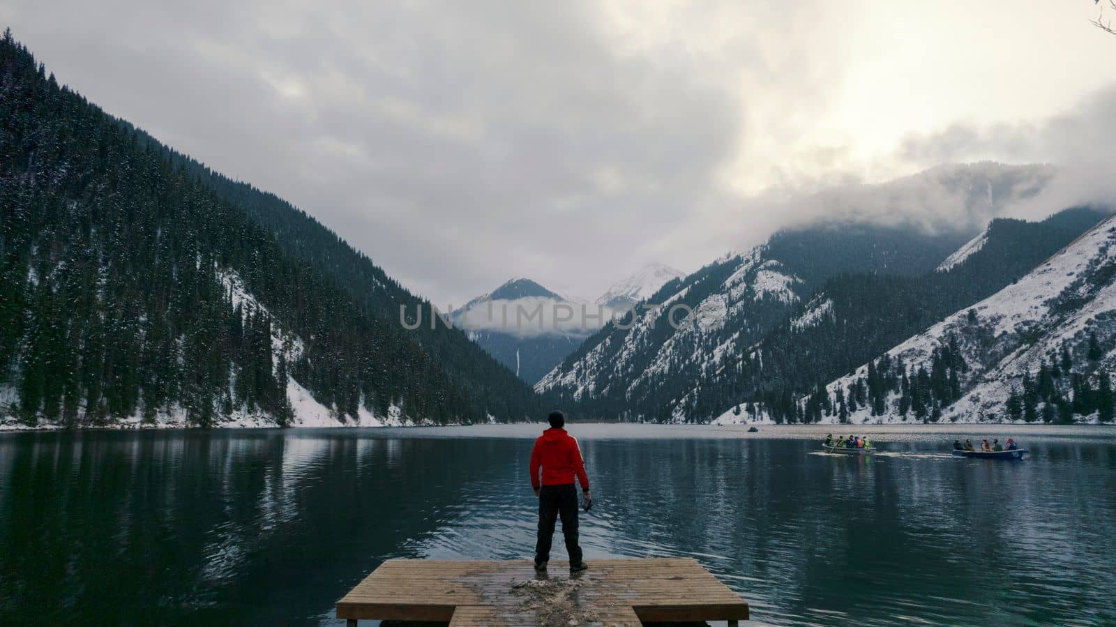 The guy standing on the pier admires mountain lake by Passcal
