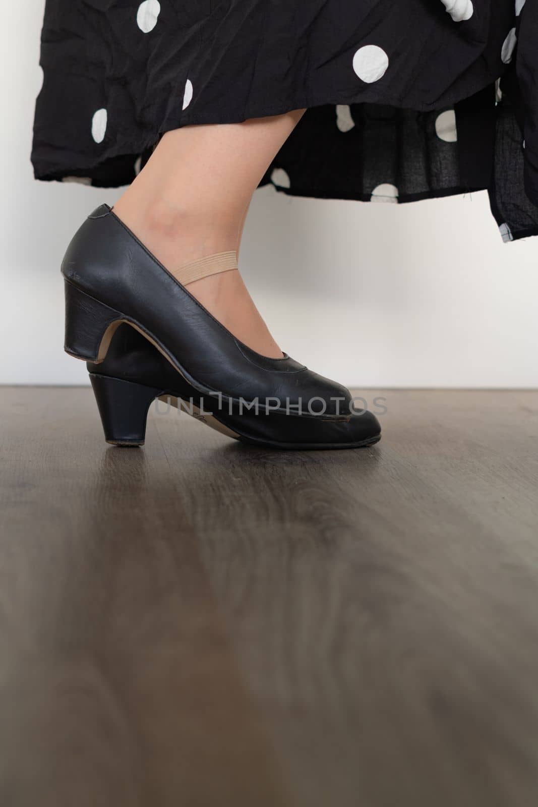 legs of woman dancing flamenco with black clothes on wooden floor and white background