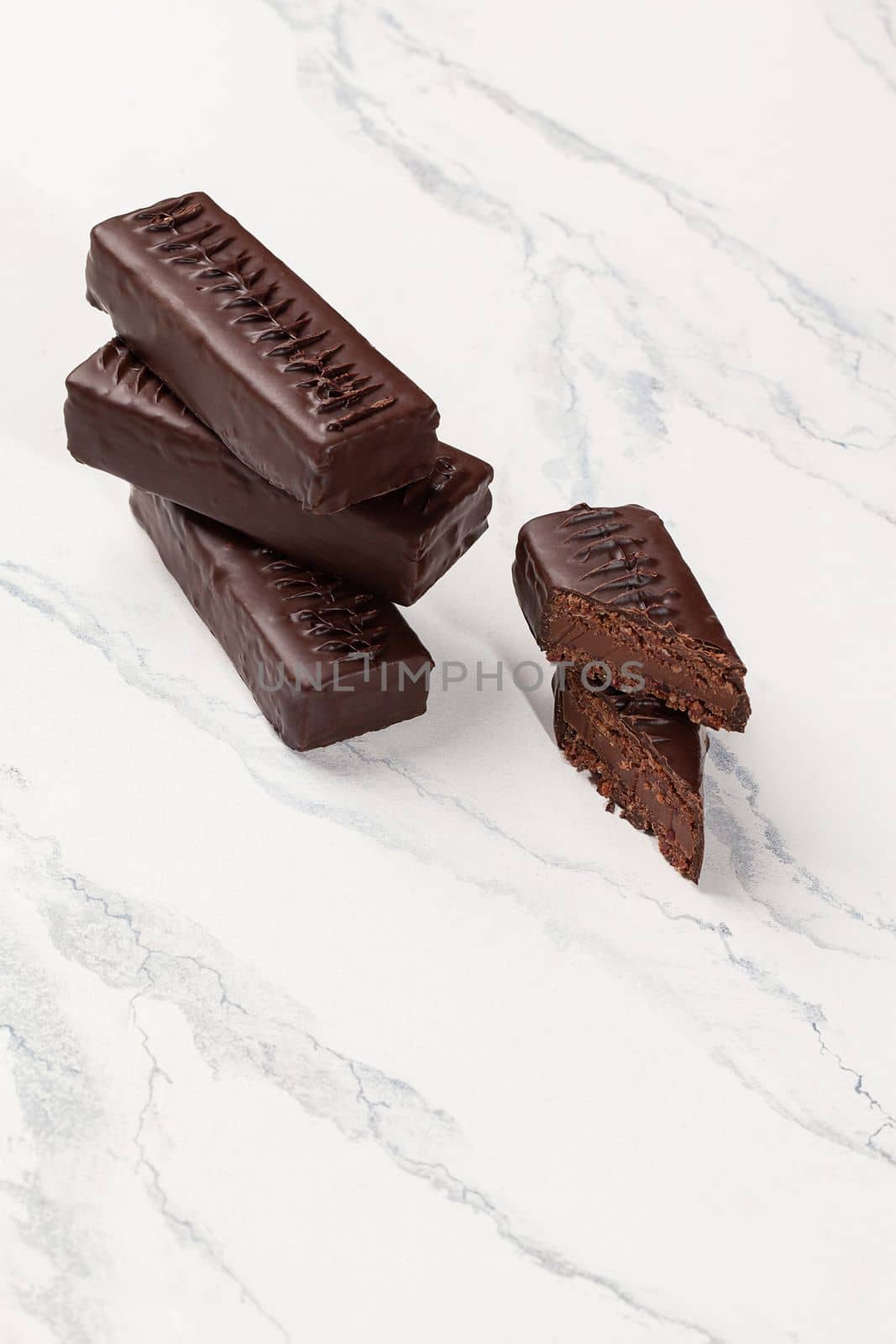 Dark chocolate bars with filling of grounded dried fruits, honey and nuts without sugar on light background. Healthy sweets during weight loss