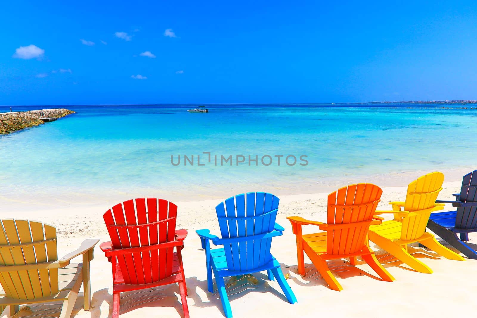 Colorful wooden chairs on white sand beach in Aruba, Duth Caribbean at sunny day