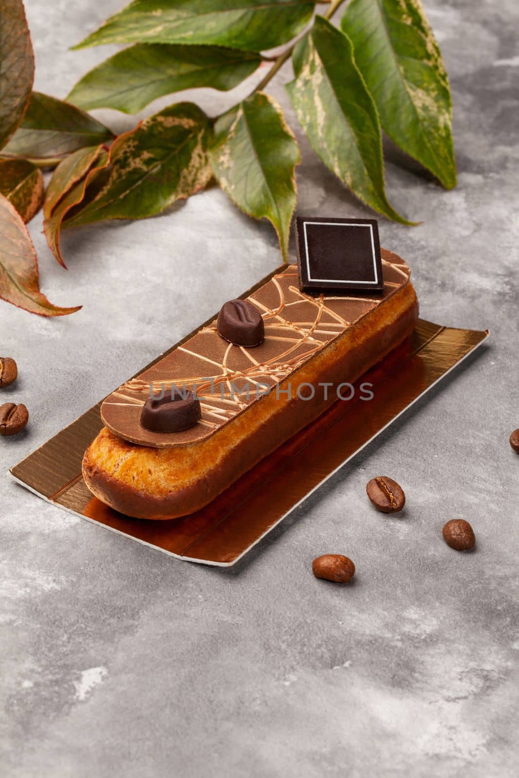 Chocolate glazed eclair with coffee custard on gold cardboard by nazarovsergey